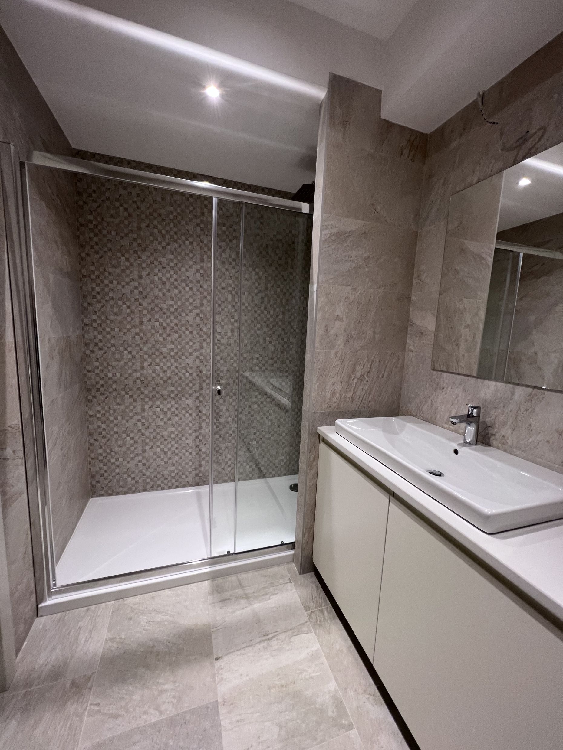Modernes Badezimmer mit Duschkabine und Waschtischunterschrank in einer Wohnung, Stadt Kotor, Montenegro.