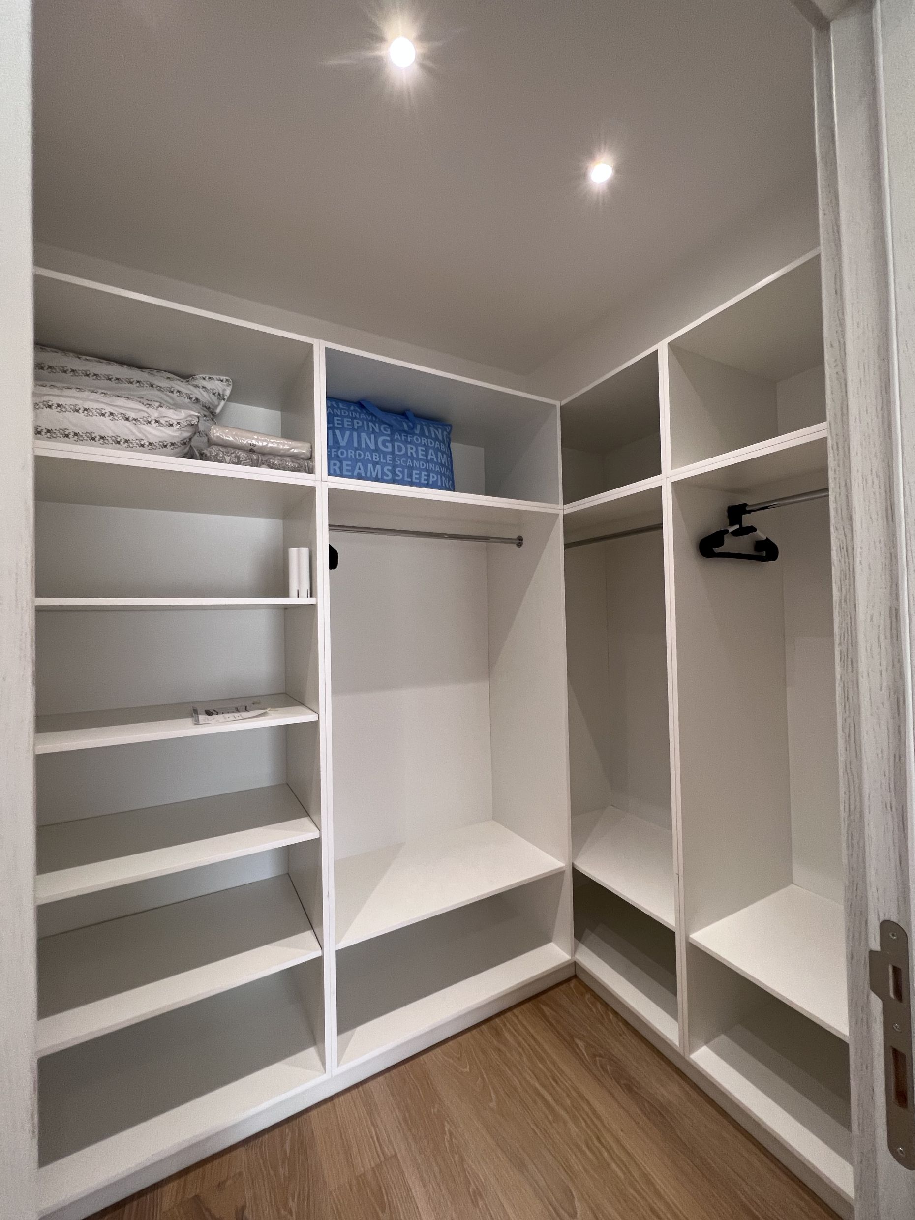 Geräumiger begehbarer Kleiderschrank mit weißen Regalen und Kleiderstangen in einer Wohnung, Stadt Kotor, Montenegro.