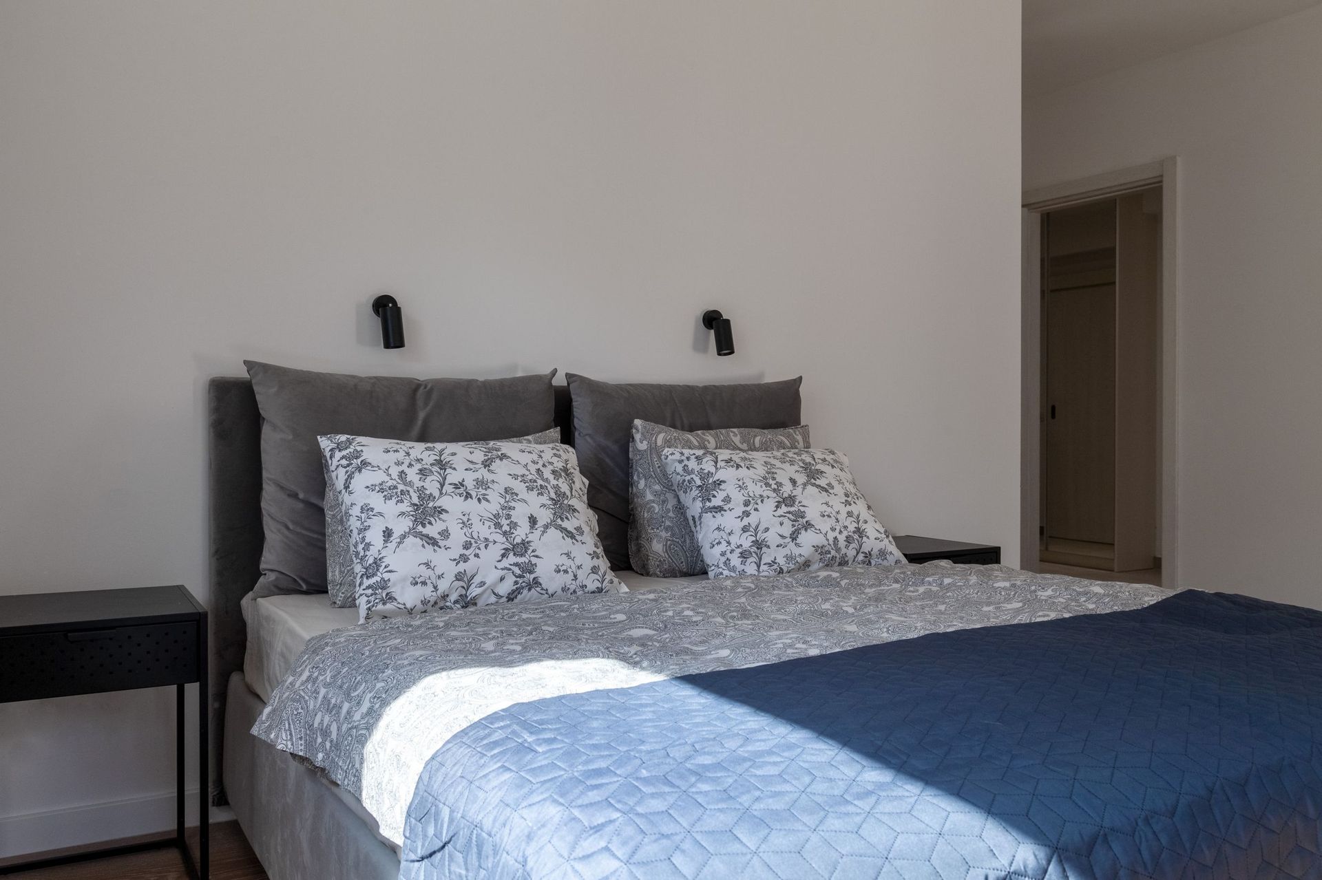 Modernes Schlafzimmer mit Doppelbett in einer Wohnung in Kotor, Montenegro: graue Töne, stilvolle Lampen.