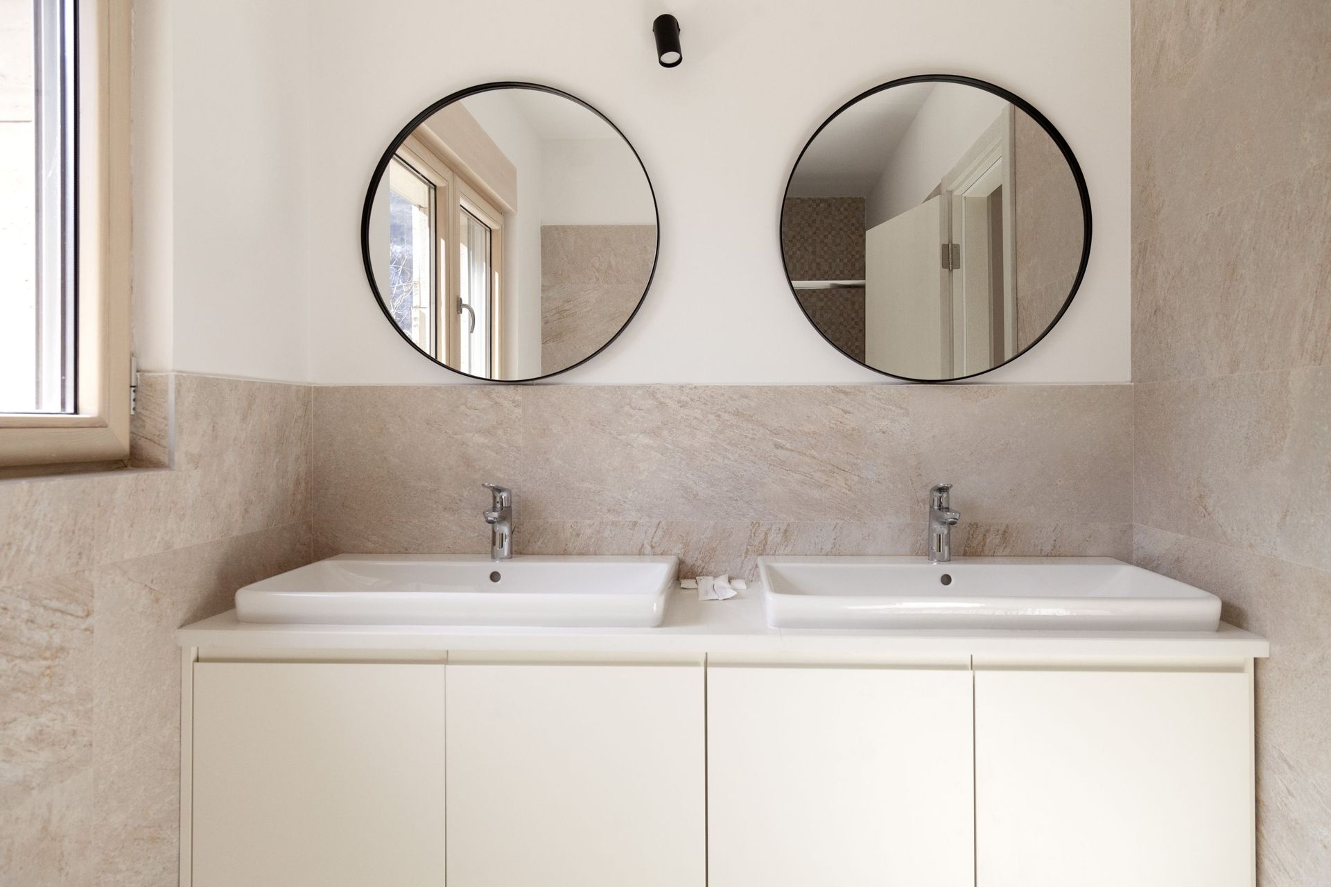 Modernes Badezimmer mit zwei Waschbecken und runden Spiegeln in einer Wohnung, Kotor, Montenegro.