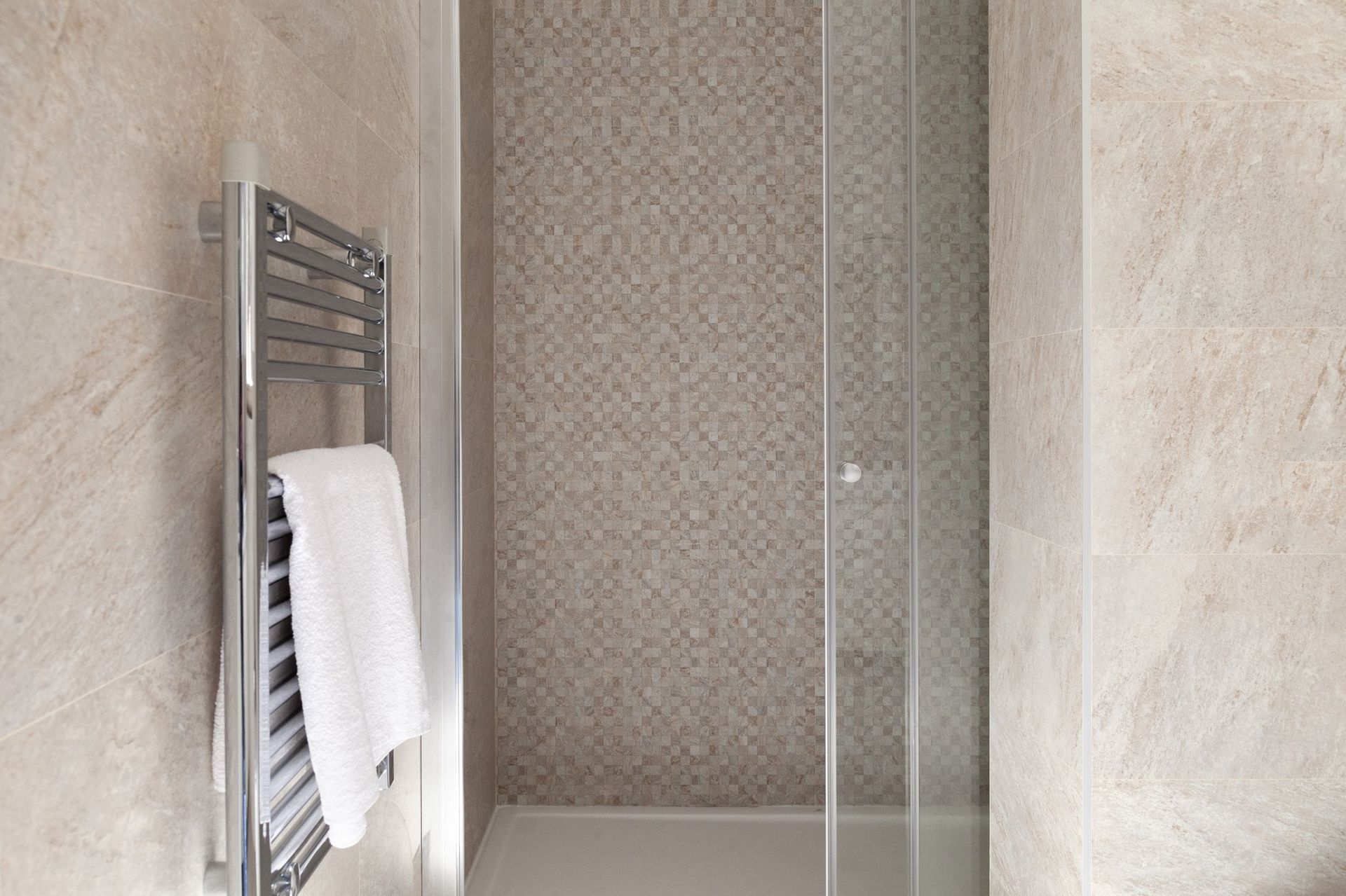 Moderne Duschkabine mit Mosaik und Handtuchheizkörper in einer Wohnung in Kotor, Montenegro.