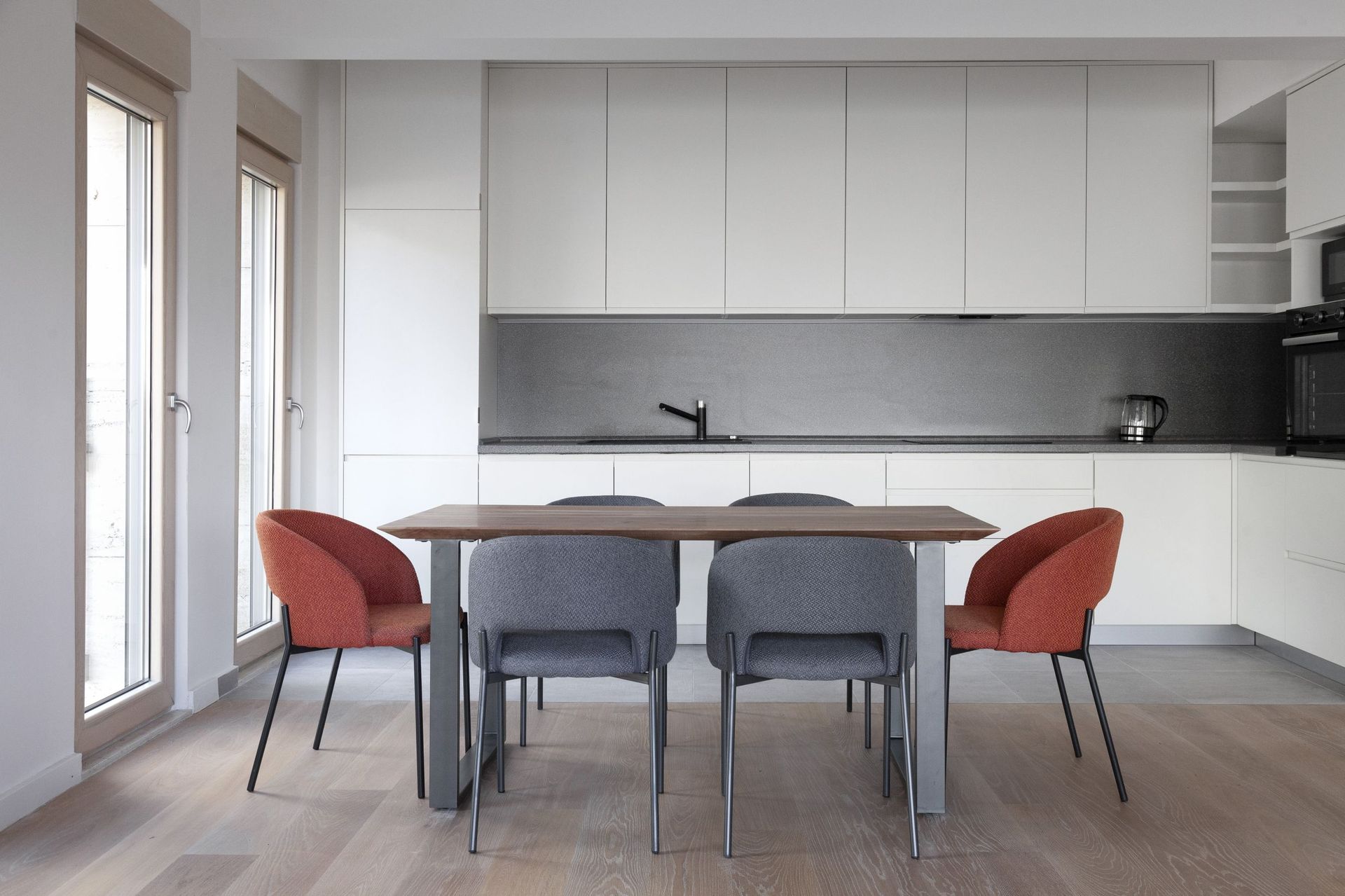 Moderne Küche in einer Wohnung in Kotor, Montenegro: weiße Einbauküche, Esstisch und stilvolle Stühle im Interieur.