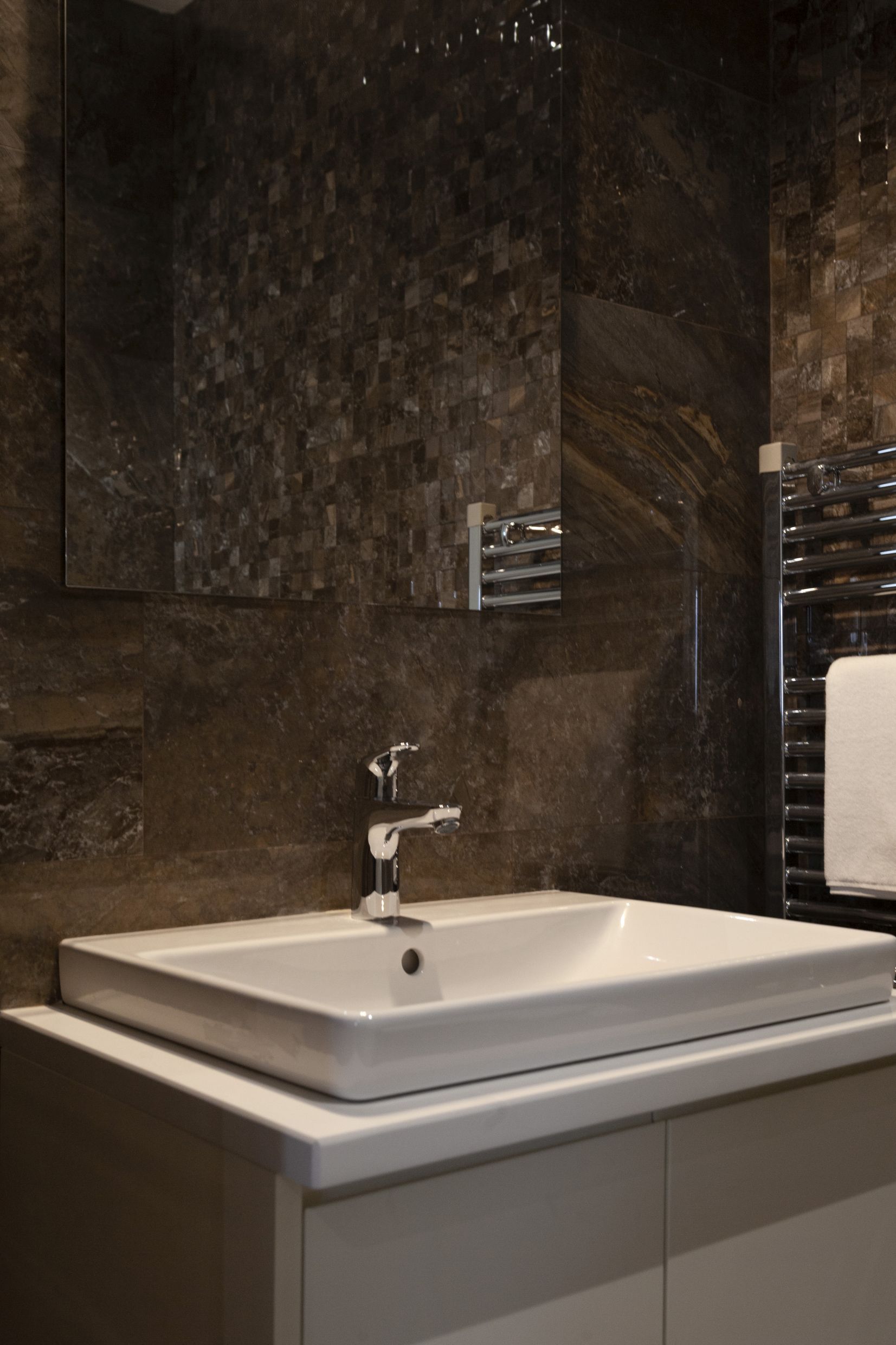 Modernes Badezimmer mit dunkler Steinverkleidung in einer Wohnung in Kotor, Montenegro: Waschbecken und Spiegel.