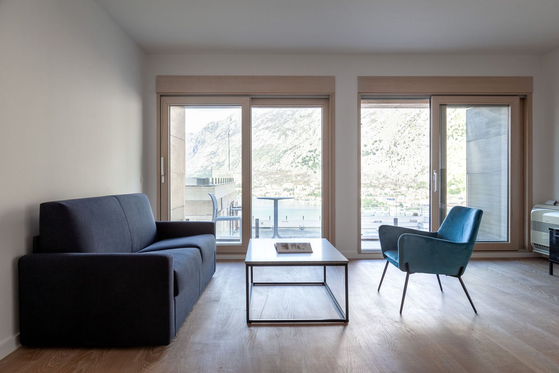 Wohnzimmer mit Panoramablick auf die Berge und die Bucht in einer Wohnung in Kotor, Montenegro: moderne Möbel und helles Interieur.