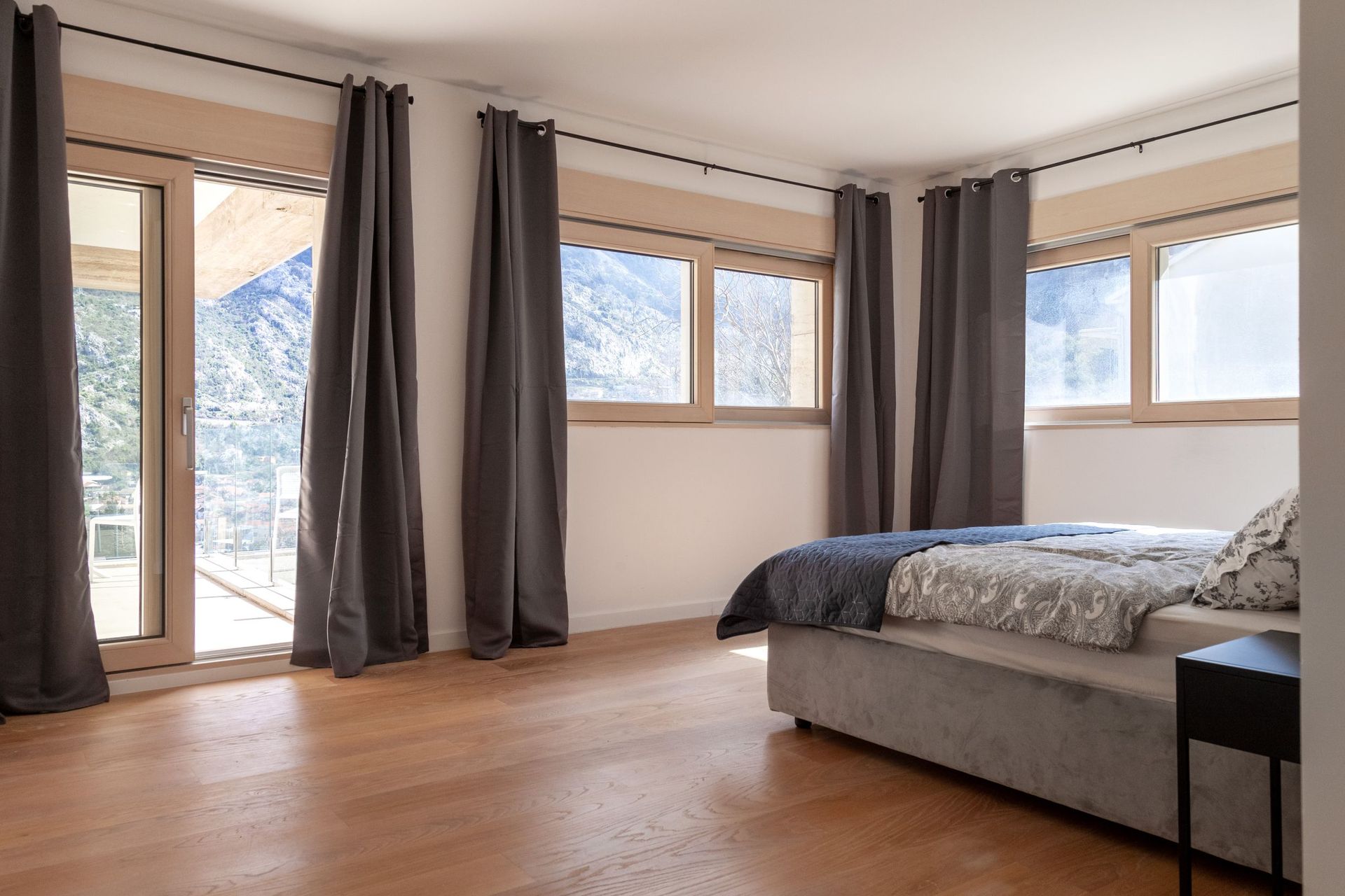 Modernes Schlafzimmer mit Doppelbett und Zugang zur Terrasse mit Bergblick in einer Wohnung, Kotor, Montenegro.