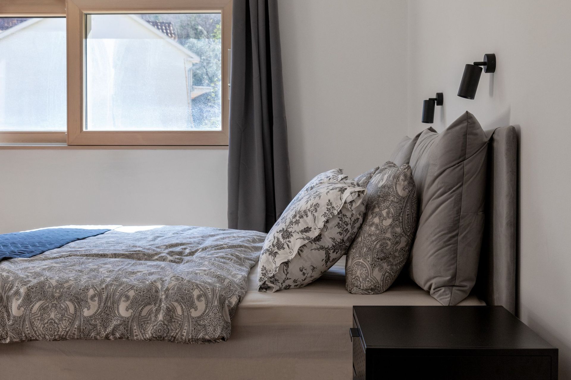 Modernes Schlafzimmer in einer Wohnung in Kotor, Montenegro: Doppelbett, stilvolle Textilien und Blick aus dem Fenster.