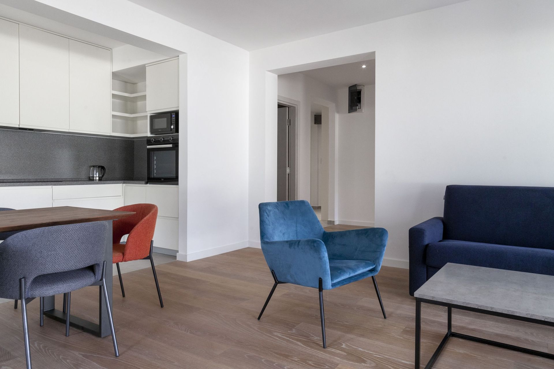Modernes Wohnzimmer mit Küche in einer Wohnung in Kotor, Montenegro: blaue Sessel, Essbereich und helle Ausstattung.