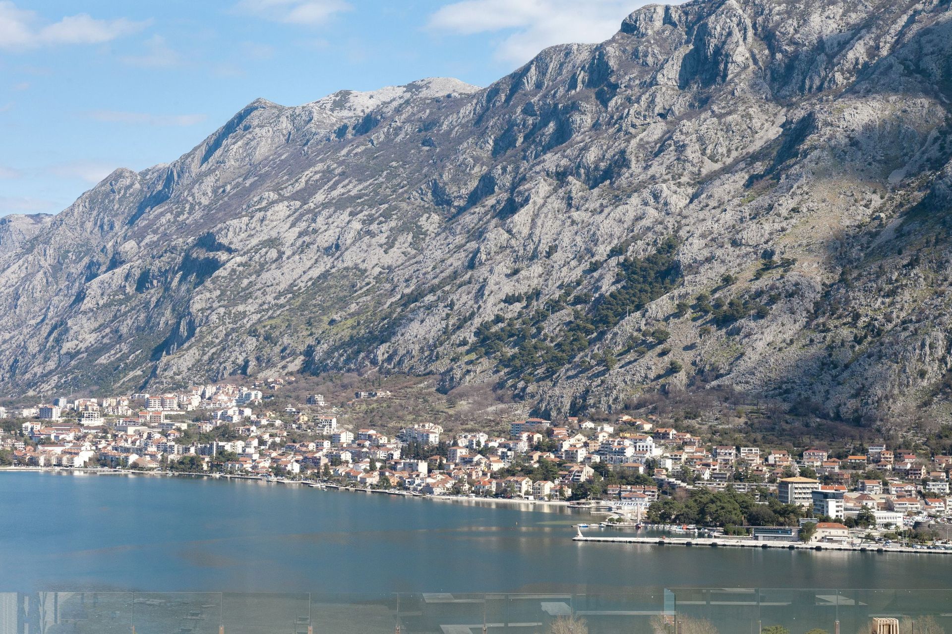 Panoramablick auf die Bucht von Kotor und die Berge aus dem Fenster einer Wohnung in Kotor, Montenegro: Küstenstadt und Meereslandschaft.