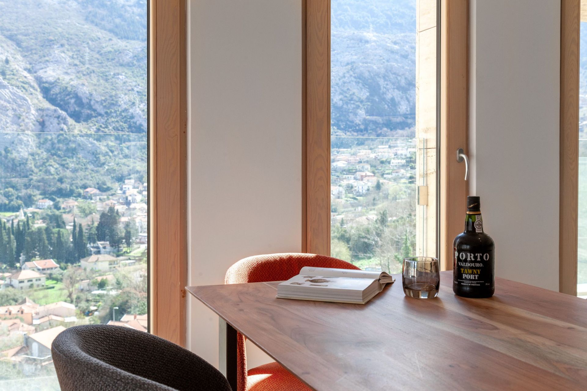 Wohnzimmer mit Panoramablick auf die Berge und die Stadt Kotor, Montenegro: Holztisch, stilvolle Sessel und gemütliches Interieur.