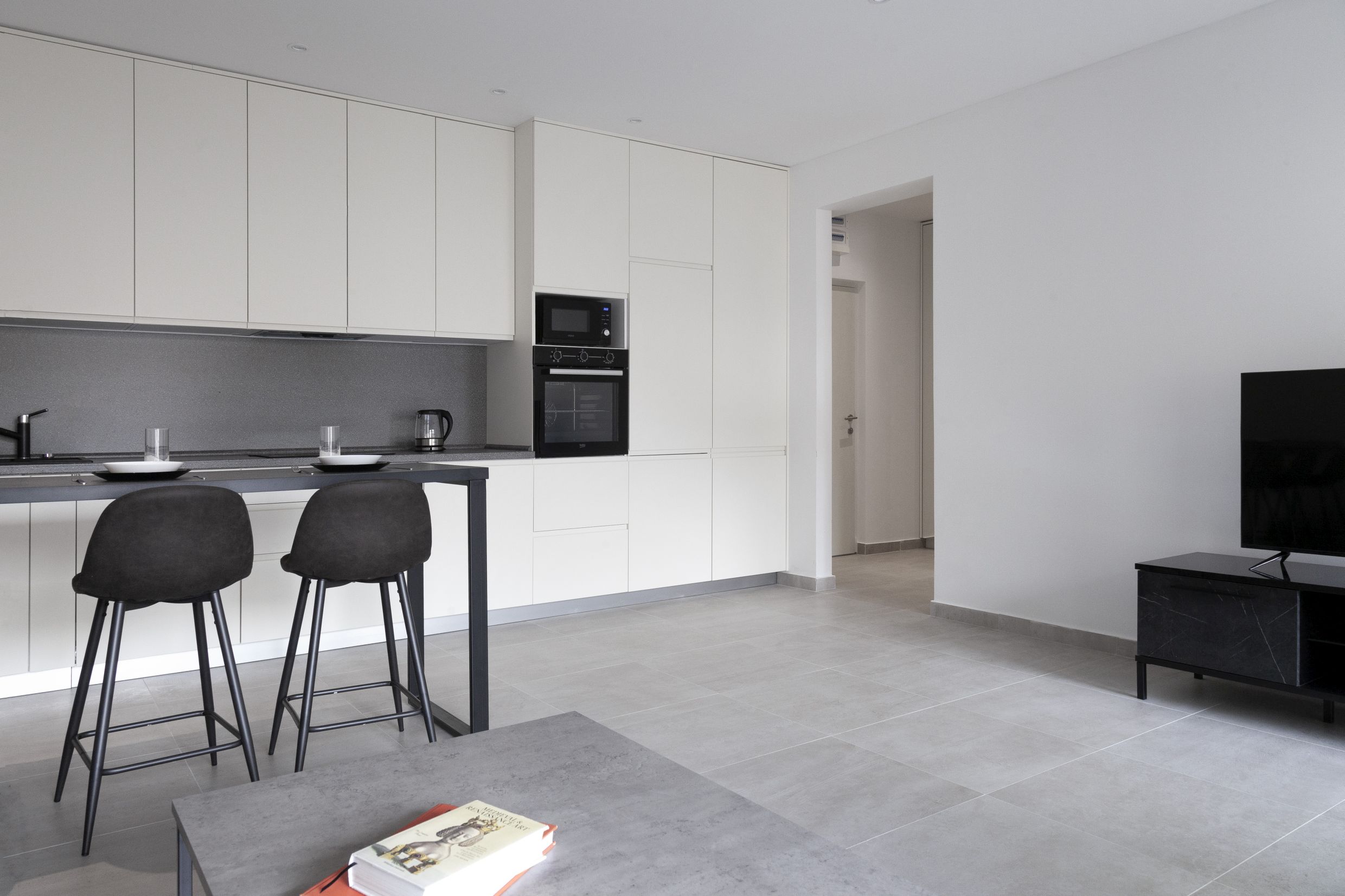 Moderne Wohnküche in einer Wohnung in Kotor, Montenegro: helle Einbauküche, Bartheke und integrierte Geräte.