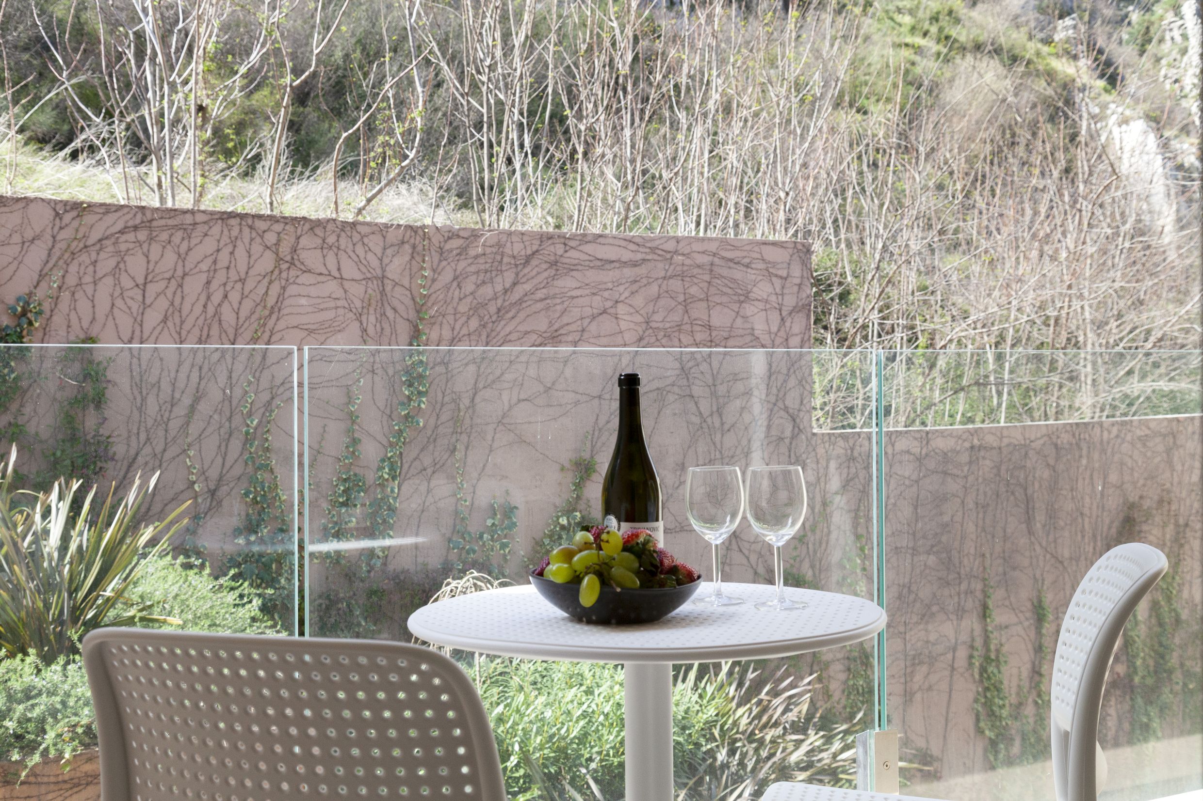 Balkon mit weißen Möbeln und Bergblick in Wohnung Nr. 2550, Kotor, Montenegro: Tisch mit Wein und Obst hinter Glas.