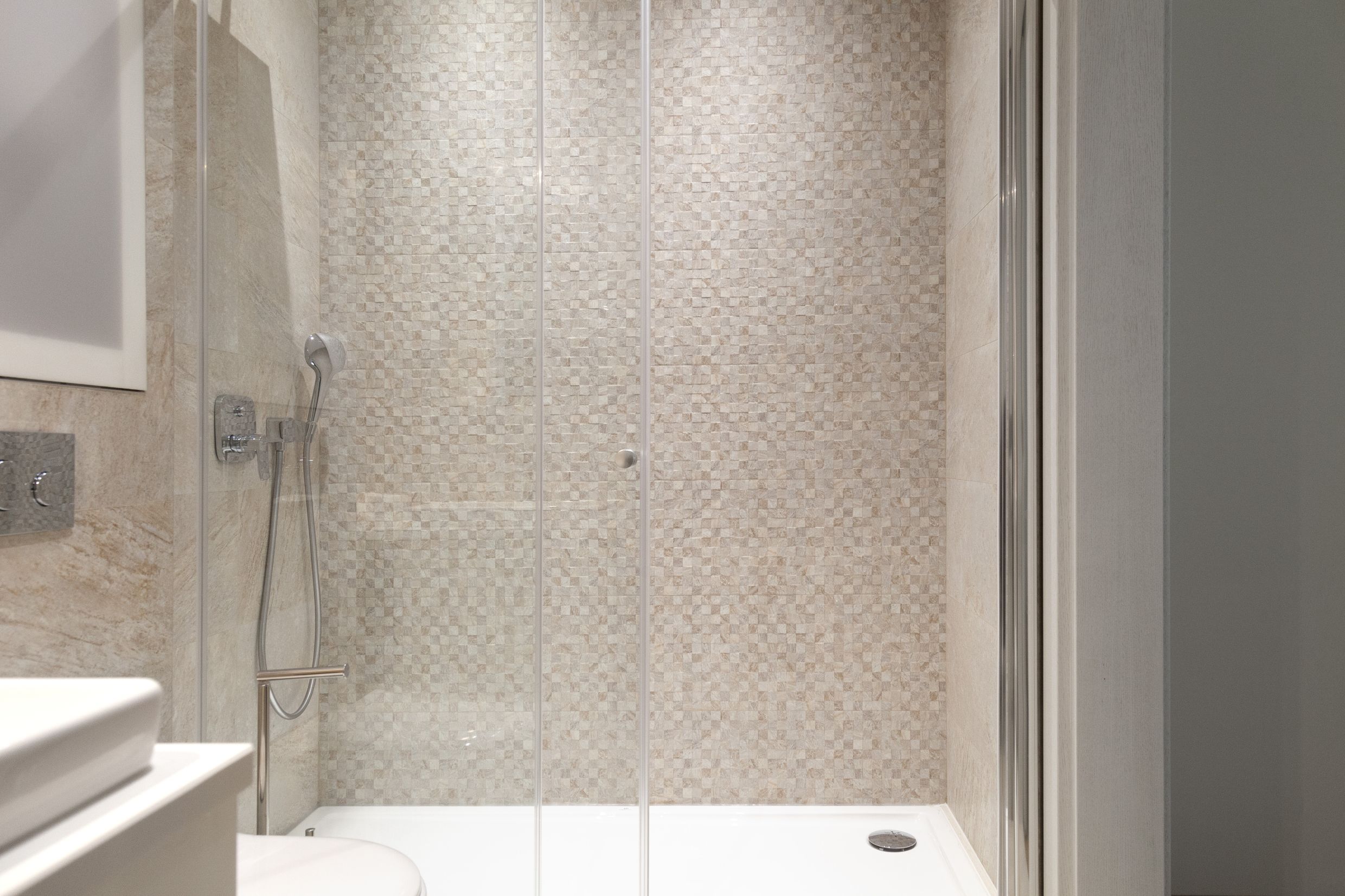 Moderne Duschkabine mit Mosaikfliesen im Badezimmer einer Wohnung in Kotor, Montenegro.
