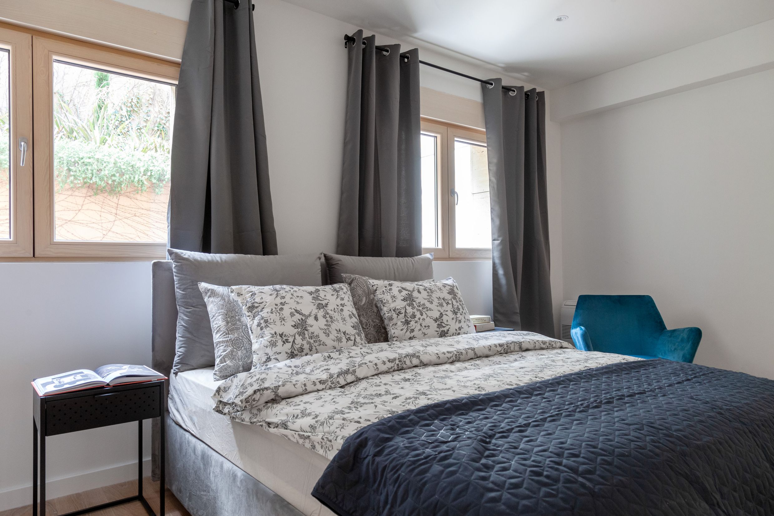 Modernes Schlafzimmer mit Doppelbett und blauem Sessel in einer Wohnung in Kotor, Montenegro.