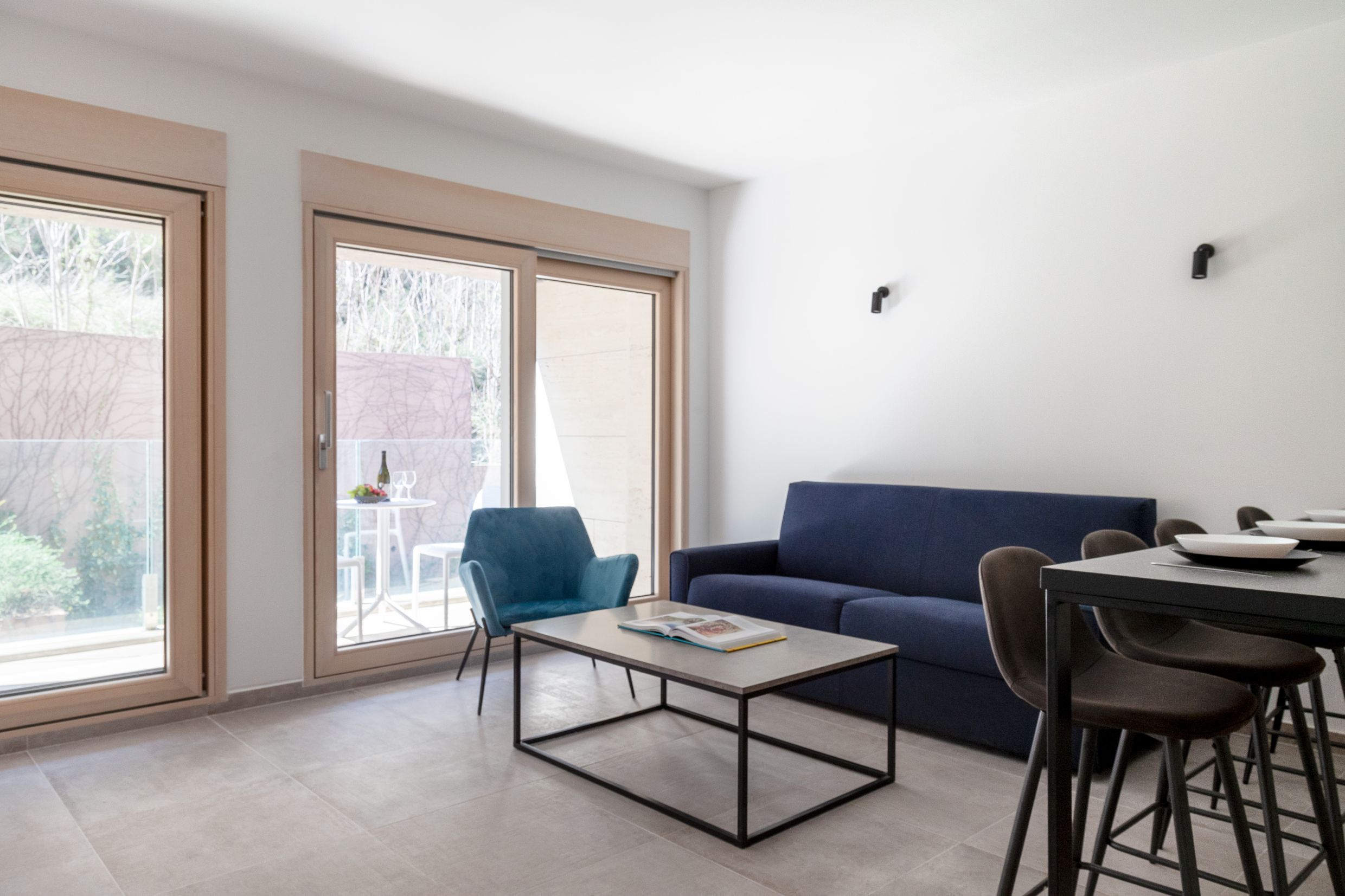 Modernes Wohnzimmer in einer Wohnung in Kotor, Montenegro: blaues Sofa, Sessel, Tisch und Ausgang zur Terrasse mit Aussicht.