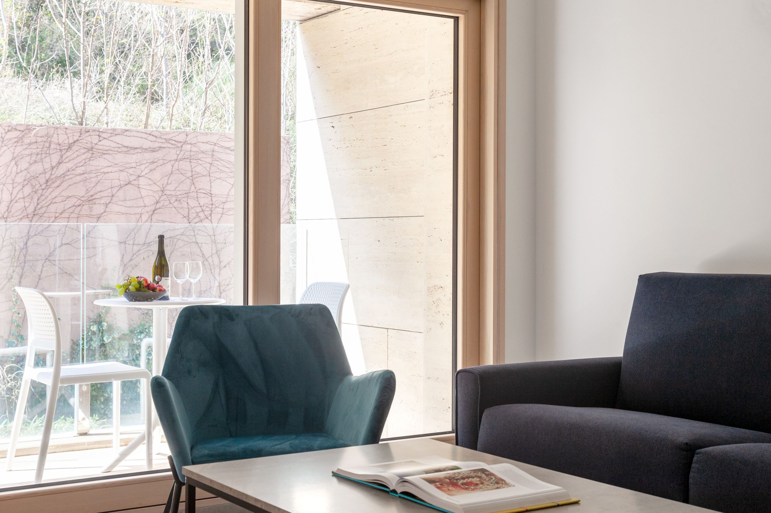 Wohnzimmer in einer modernen Wohnung in Kotor, Montenegro: Sessel, Sofa und Zugang zur Terrasse mit Blick auf den Garten.