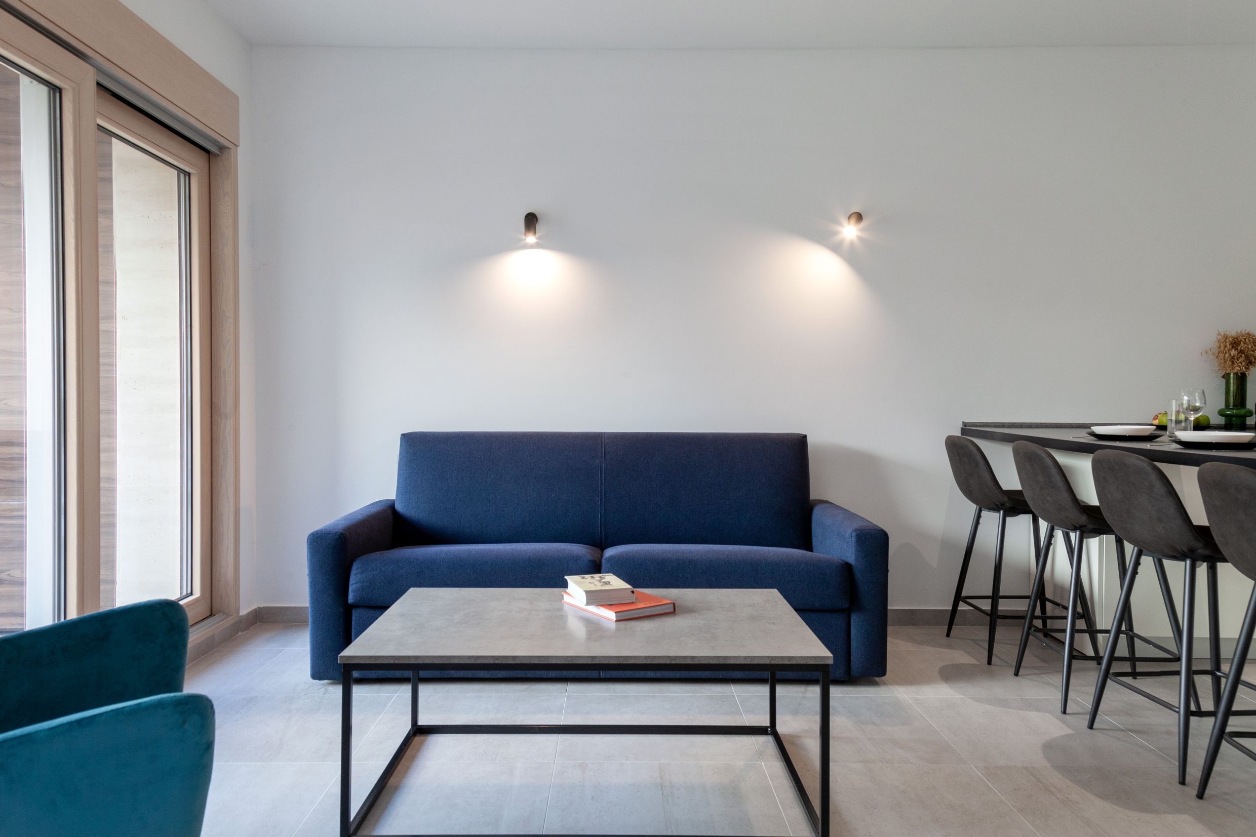 Modernes Wohnzimmer mit blauem Sofa und Bartheke in einer Wohnung in Kotor, Montenegro. Innenraum mit Panoramafenster.