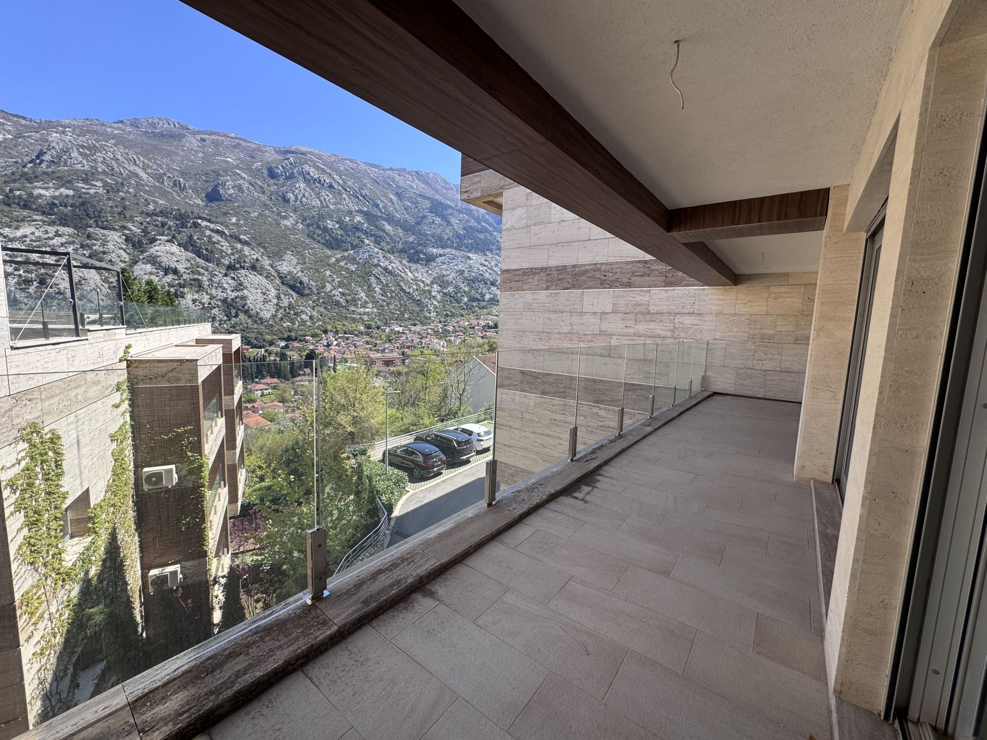 Prostran balkon sa kamenim oblogama i panoramskim pogledom na planine u modernom stanu, Kotor, Crna Gora.