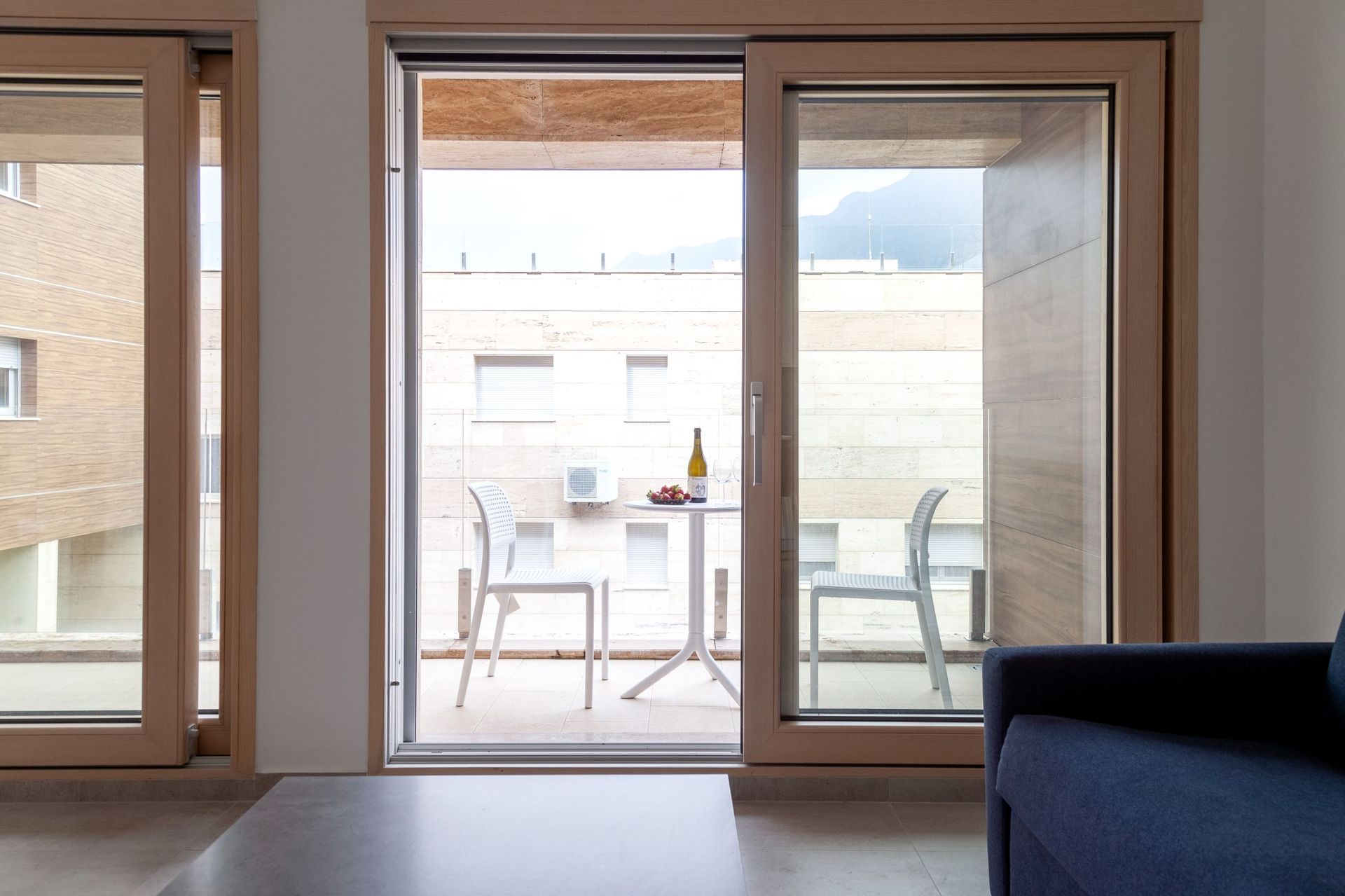 Blick vom Wohnzimmer auf die Terrasse mit Möbeln in einer modernen Wohnung in Kotor, Montenegro. Panoramafenster und helles Interieur.