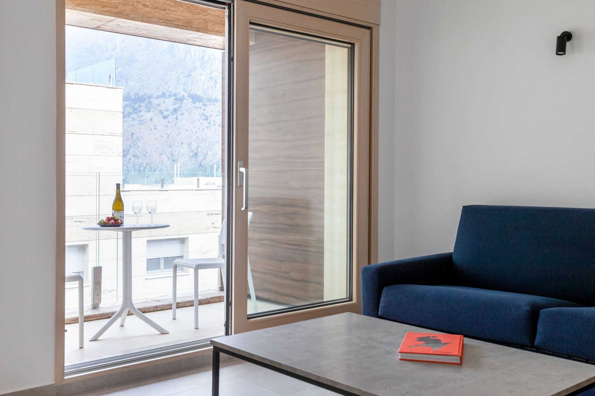 Wohnzimmer mit blauem Sofa und Zugang zur Terrasse mit Bergblick in einer Wohnung in Kotor, Montenegro.