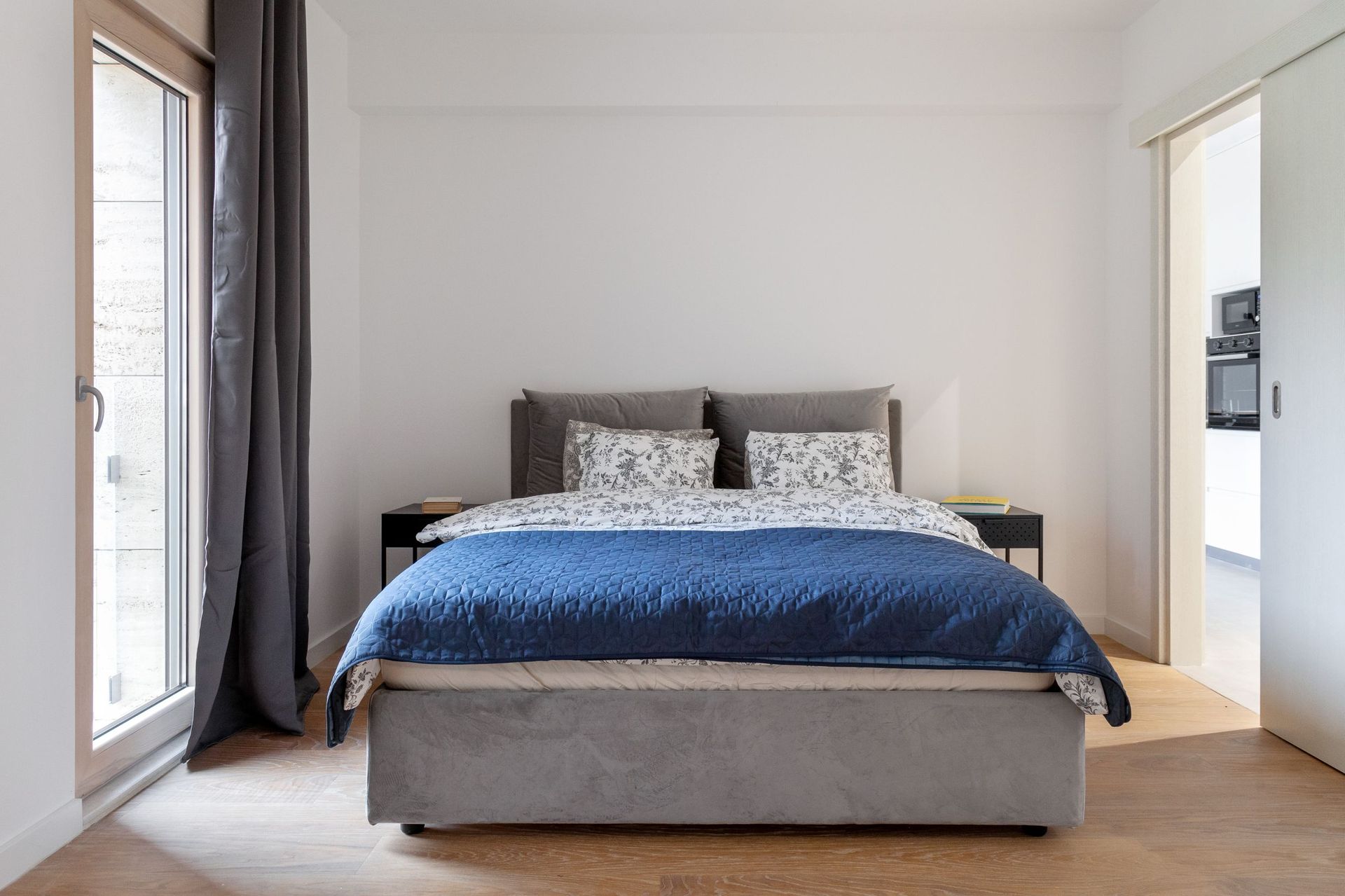 Modernes Schlafzimmer mit Doppelbett in einer Wohnung in Kotor, Montenegro: helles Interieur, Parkett und Zugang zum Balkon.