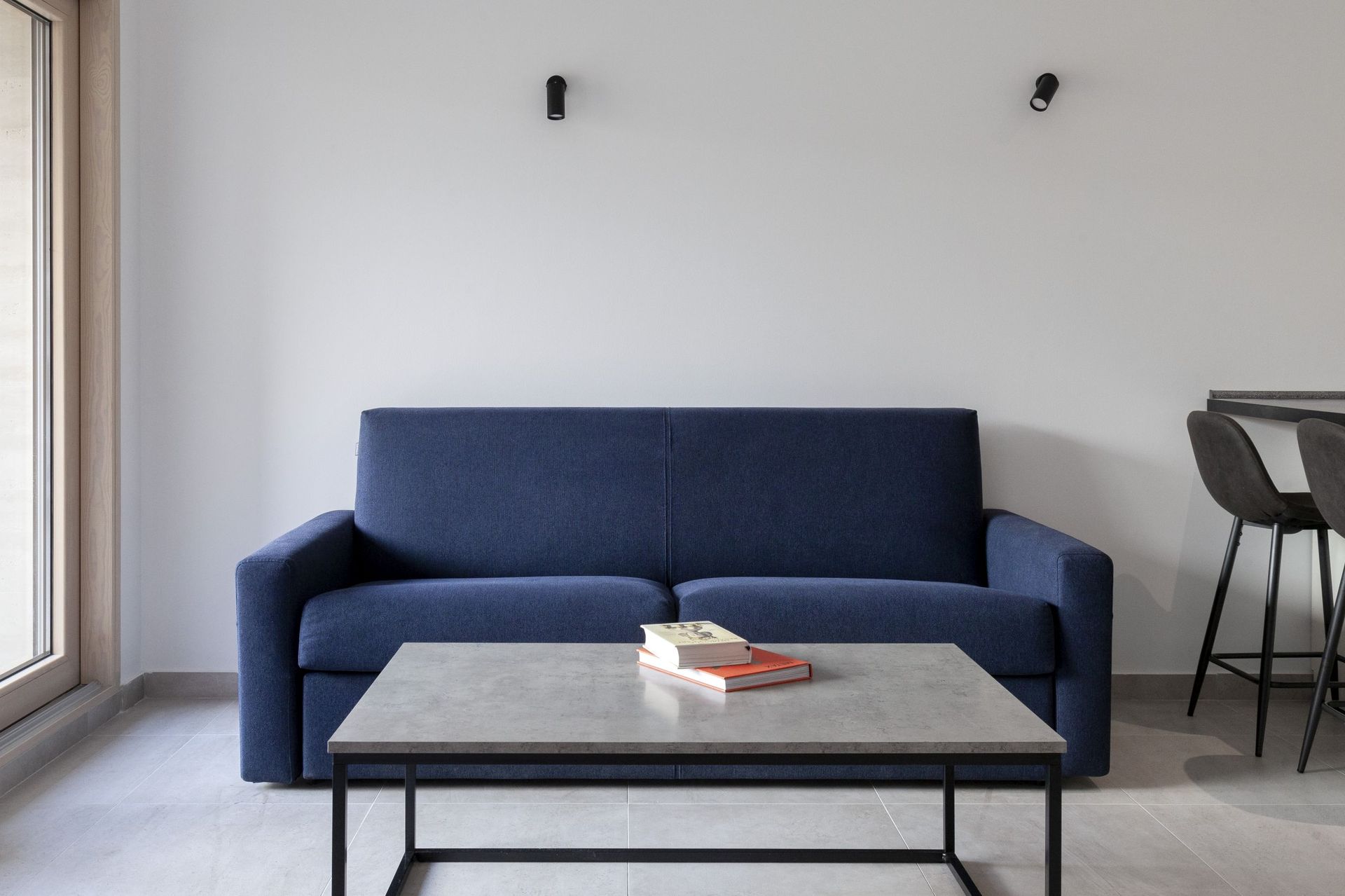 Blaues Sofa und Couchtisch im Interieur einer modernen Wohnung in Kotor, Montenegro. Stilvolles Wohnzimmer mit Panorama.