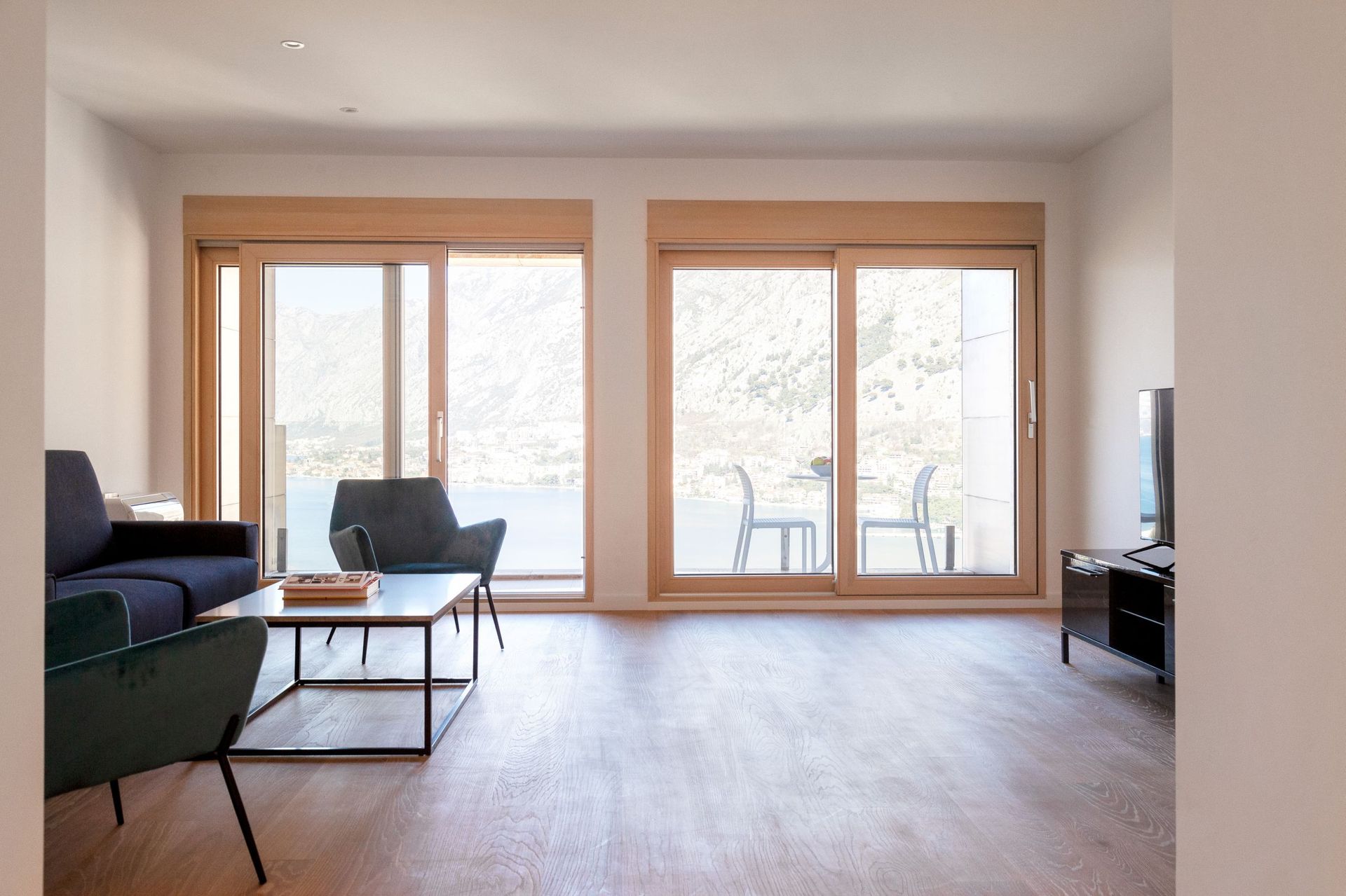 Modernes Wohnzimmer in einer Wohnung in Kotor, Montenegro, mit Panoramablick auf das Meer und die Berge durch Schiebefenster.