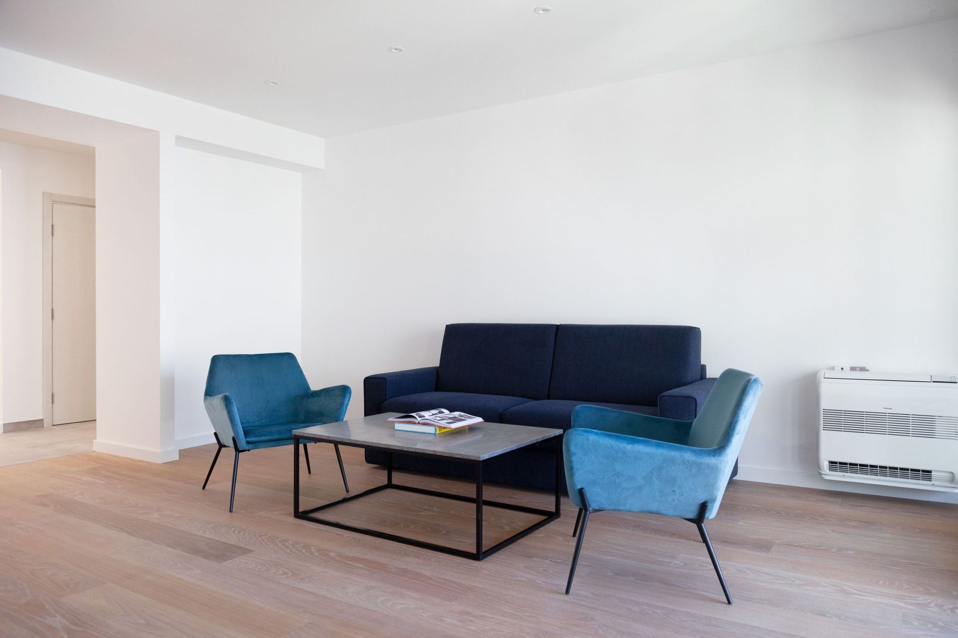 Modernes Wohnzimmer mit blauem Sofa und Sesseln in einer Wohnung in Kotor, Montenegro. Helles Interieur mit Parkett.