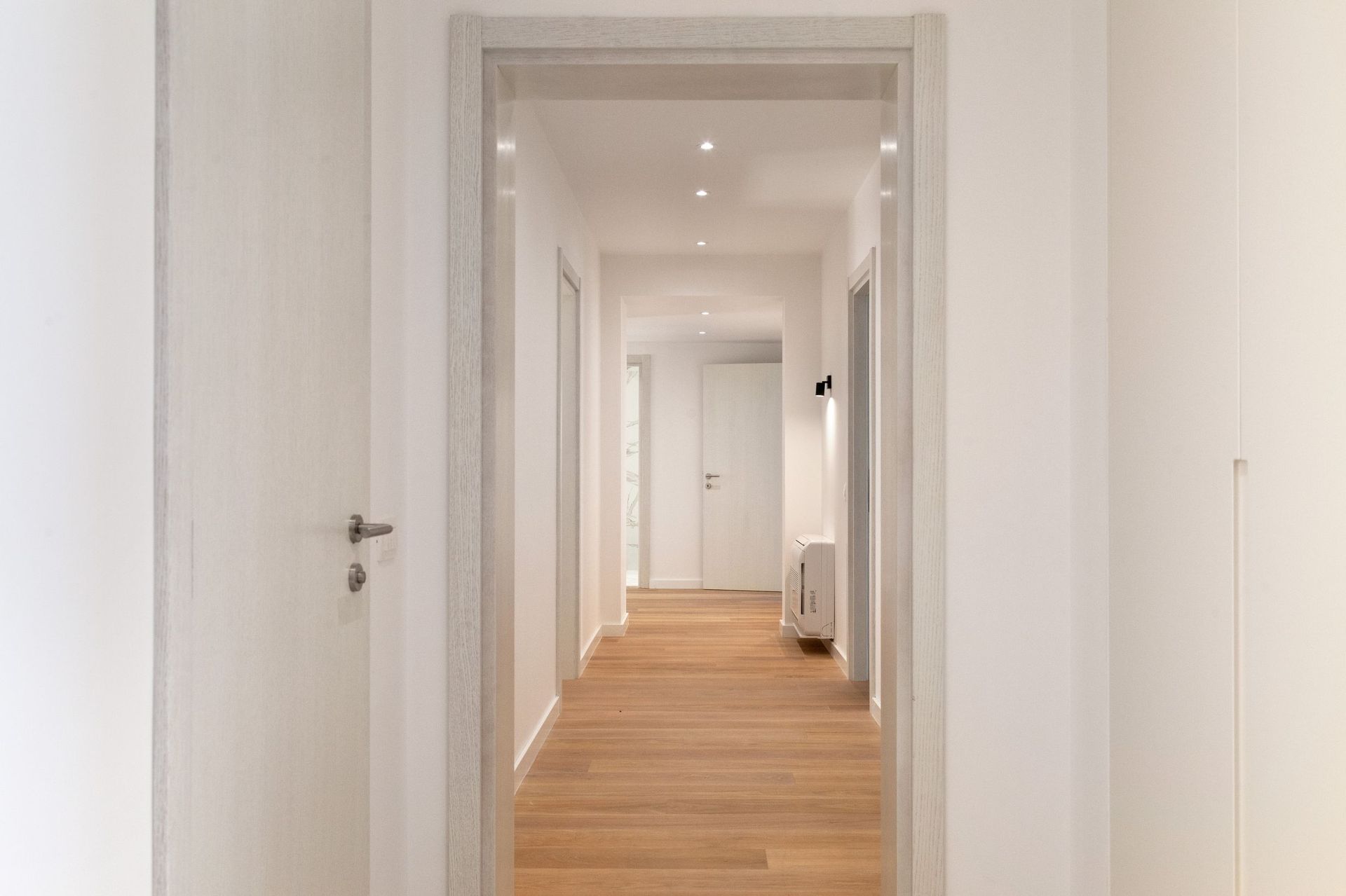 Heller Flur mit Holzboden und weißen Türen in einer modernen Wohnung, Kotor, Montenegro.