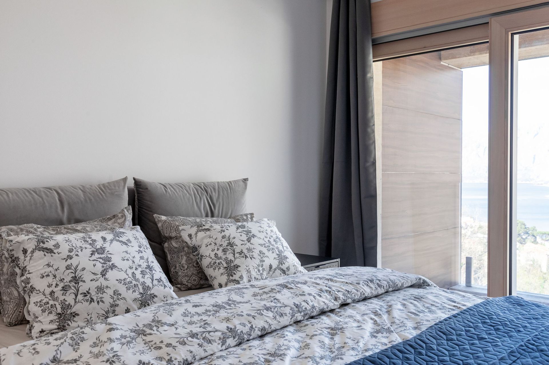 Modernes Schlafzimmer in einer Wohnung in Kotor, Montenegro, mit Doppelbett und Panoramablick auf das Meer aus dem Fenster.