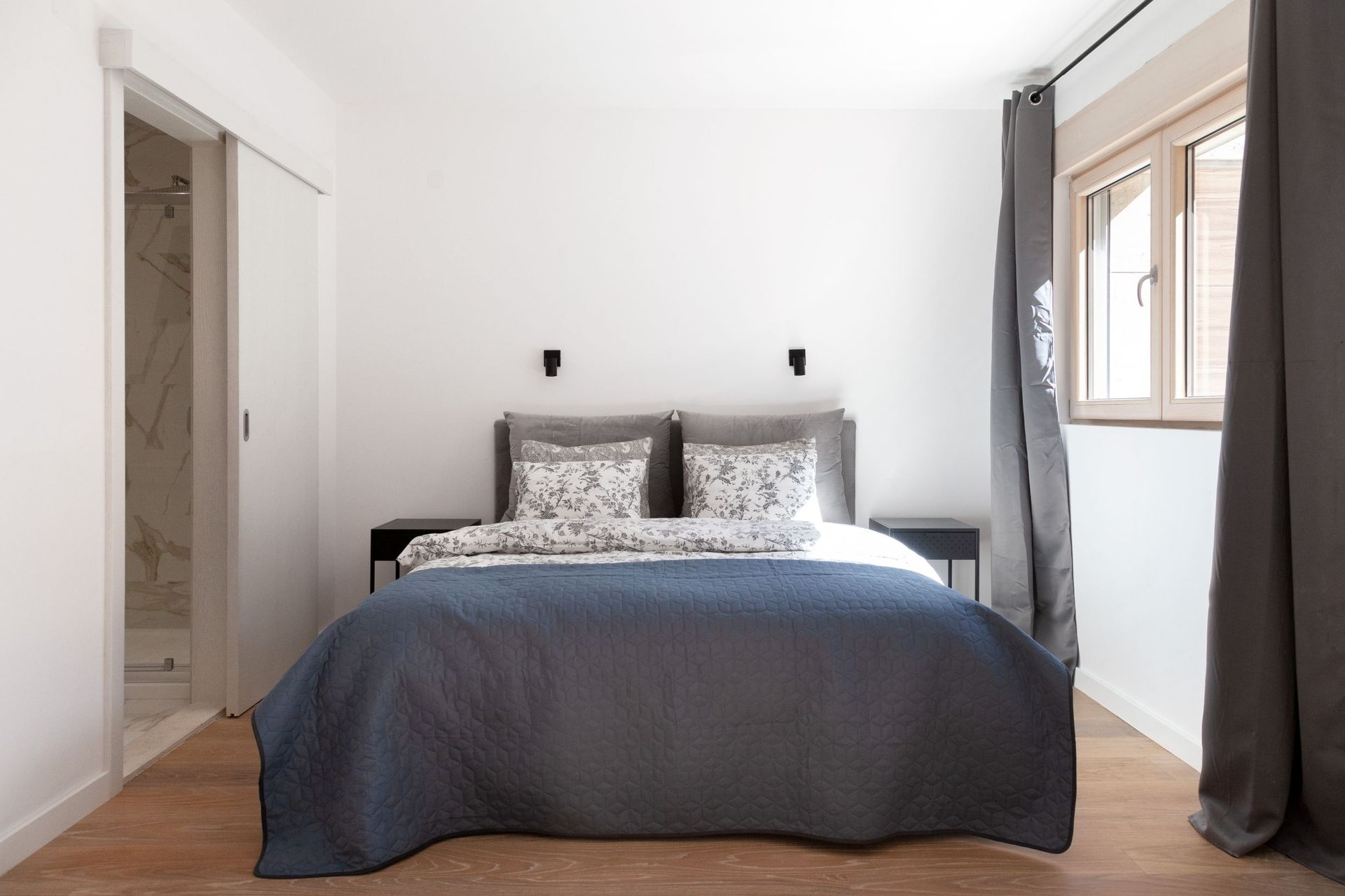 Modernes Schlafzimmer in einer Wohnung in Kotor, Montenegro: Doppelbett, Holzboden und Eingang zum Badezimmer.