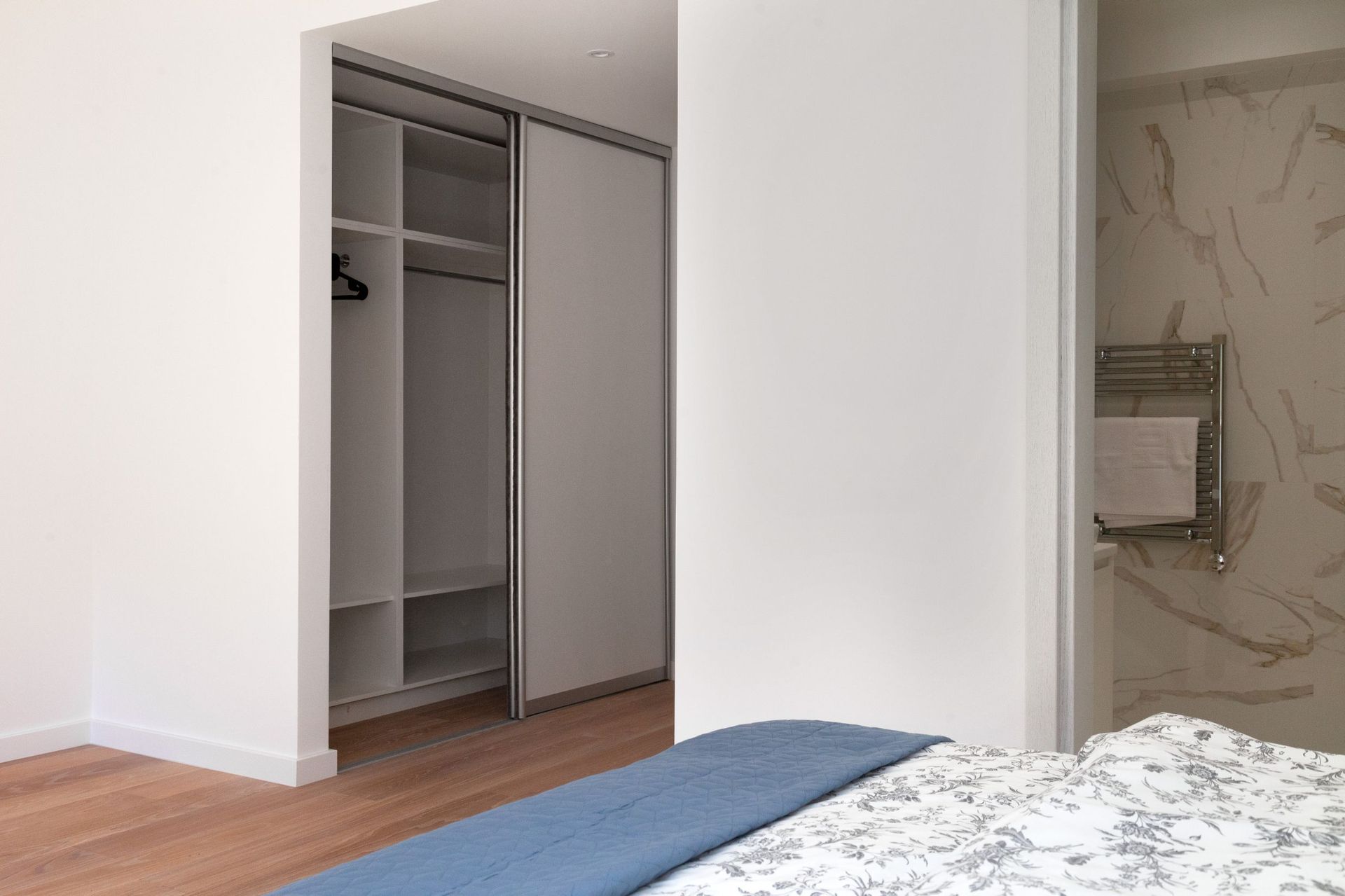 Schlafzimmer mit Ankleidezimmer und Badezimmer in einer modernen Wohnung in Kotor, Montenegro: helles Interieur und Ausstattung.