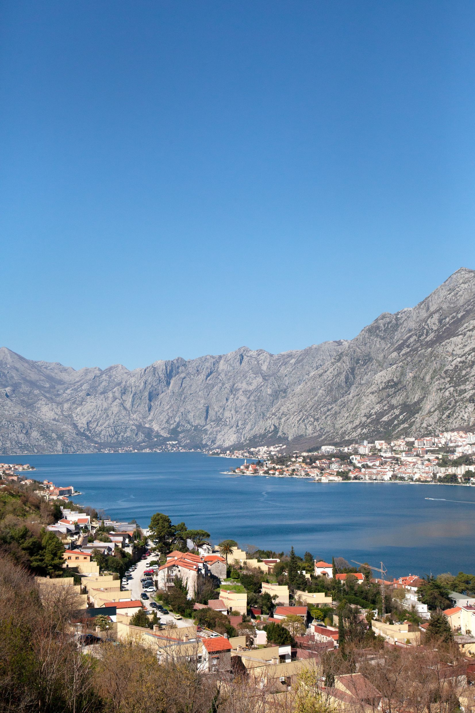 Panoramablick auf die Bucht von Kotor und die Berge in Kotor, Montenegro: Küstenhäuser mit roten Dächern und Meereslandschaft.