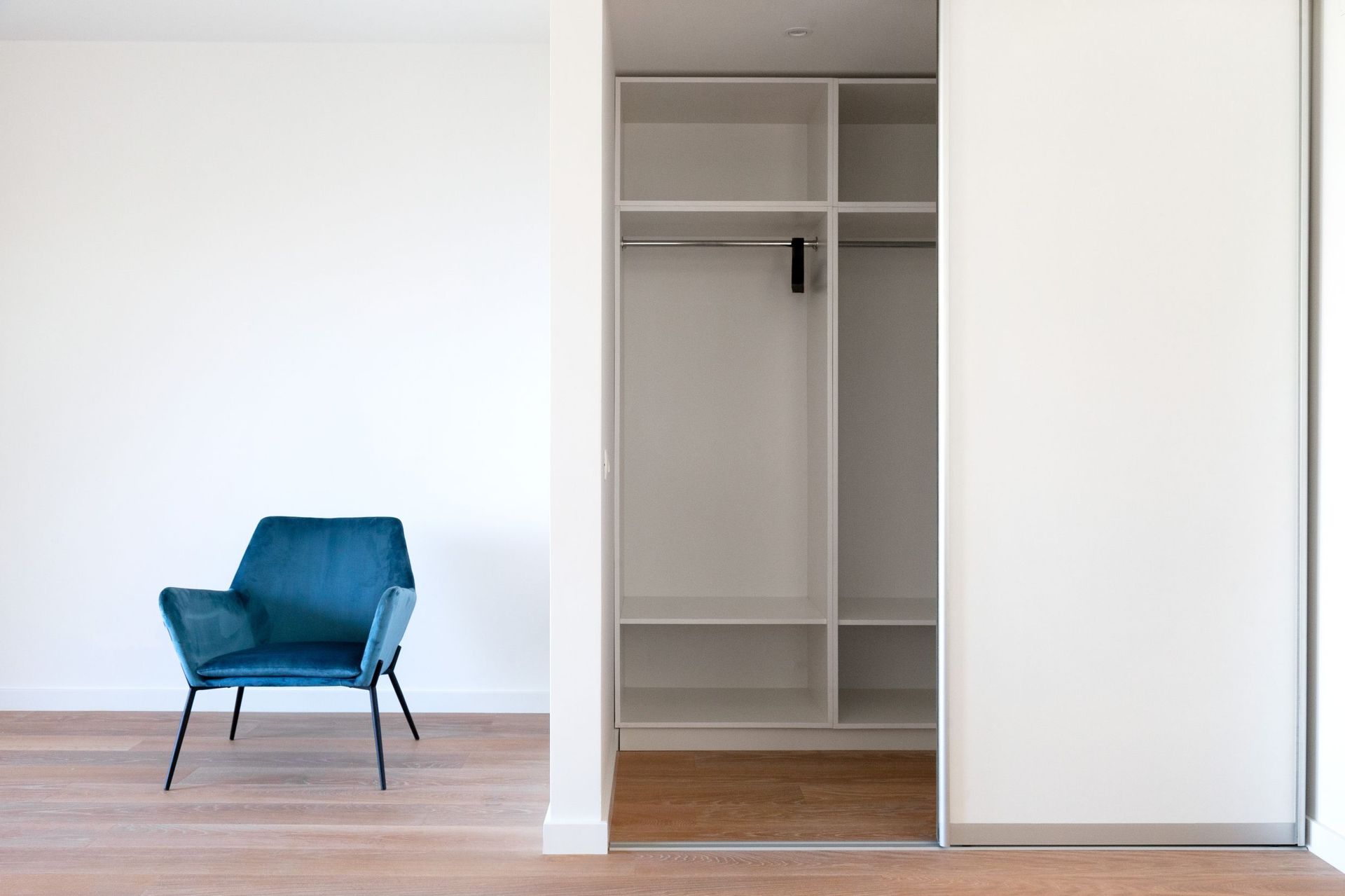 Modernes Schlafzimmer in einer Wohnung in Kotor, Montenegro: blauer Samtsessel, Einbauschrank und Parkettboden.