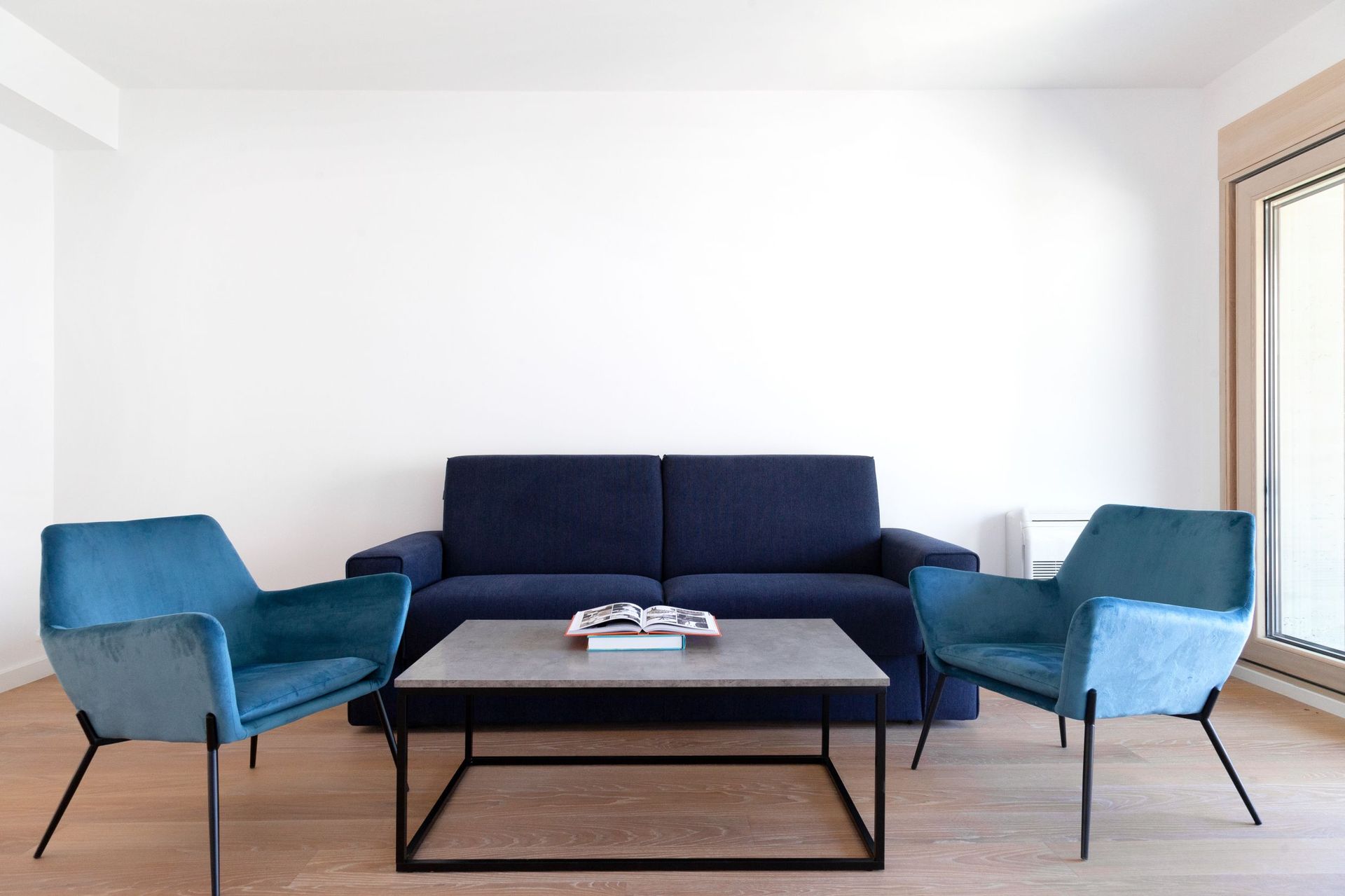Modernes Wohnzimmer in einer Wohnung in Kotor, Montenegro: blaues Sofa, Sessel, Couchtisch und helles Interieur.