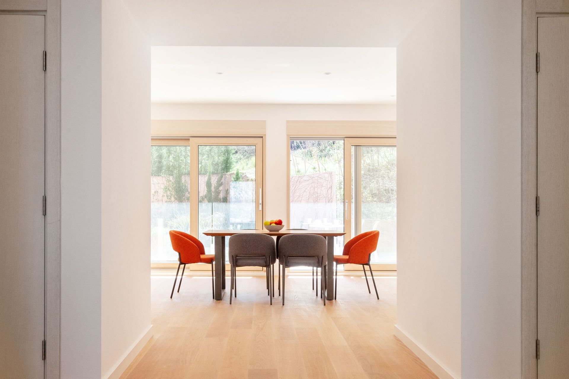 Moderner Essbereich in einer Wohnung in Kotor, Montenegro: Tisch mit orangefarbenen und grauen Stühlen und Panoramafenstern.