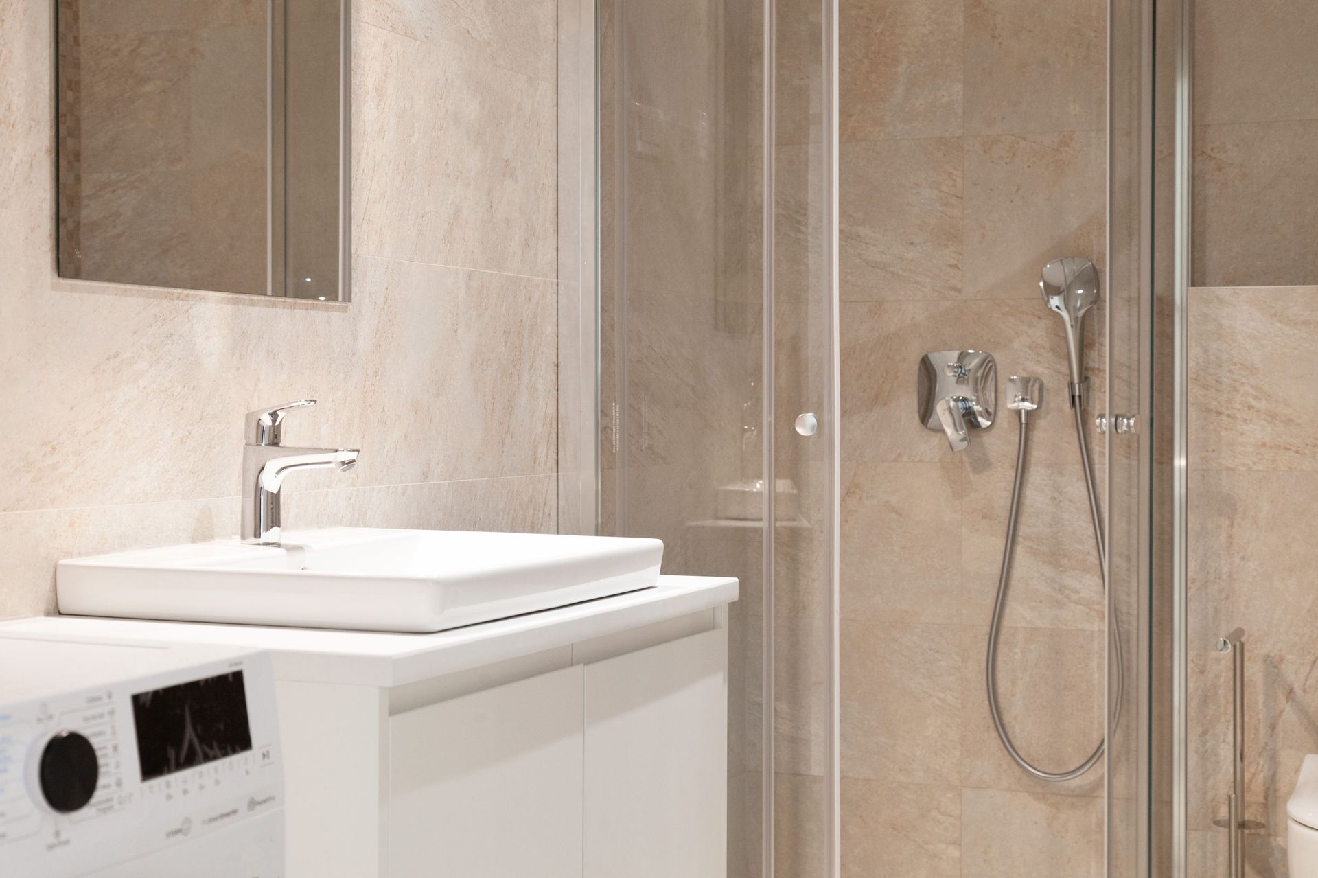 Modernes Badezimmer in einer Wohnung in Kotor, Montenegro: Duschkabine, weiße Waschtischkonsole und Fliesenverkleidung.
