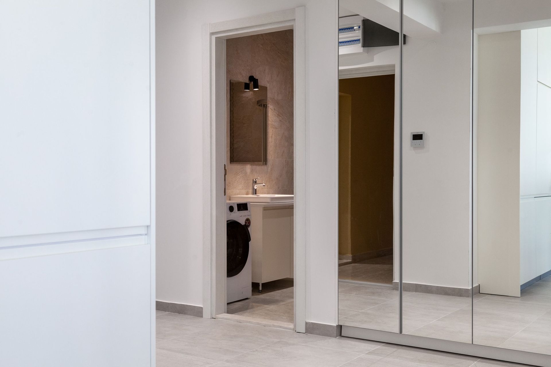 Modernes Badezimmer mit Waschmaschine in einer Wohnung, Kotor, Montenegro: helle Ausstattung und Spiegelschrank.