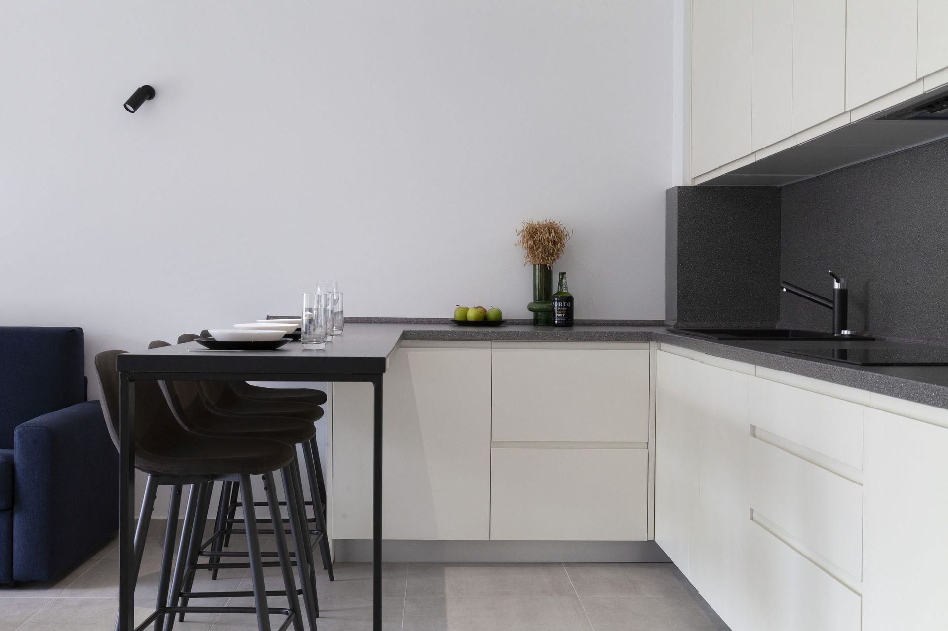 Moderne Küche mit Bartheke in einer Wohnung, Kotor, Montenegro: helle Fronten, dunkle Arbeitsplatte und stilvolle Dekoration.