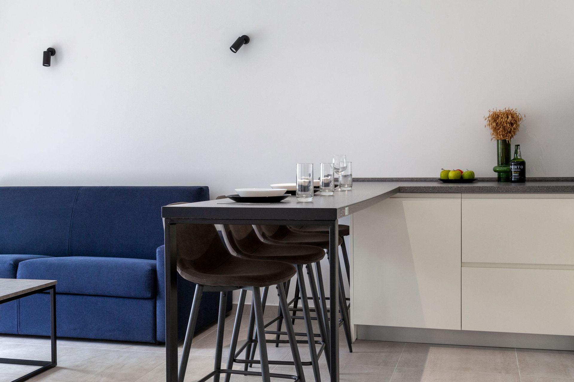 Moderne Wohnküche mit Bartheke und blauem Sofa in einer Wohnung in Kotor, Montenegro. Interieur im Loft-Stil.