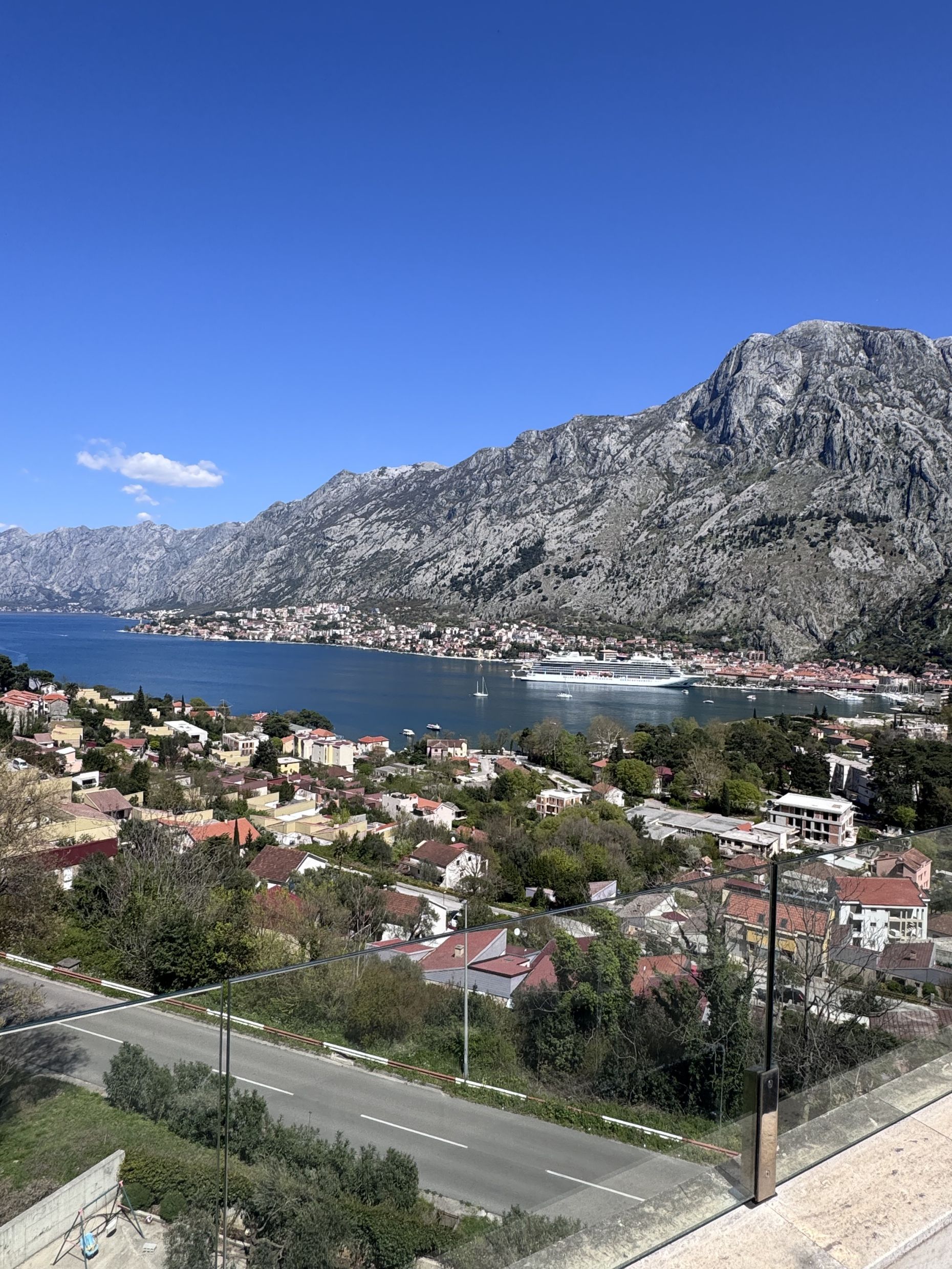 Panoramic view of the Bay of Kotor and mountains from the duplex terrace in Kotor, Montenegro, with a cruise ship in the background.