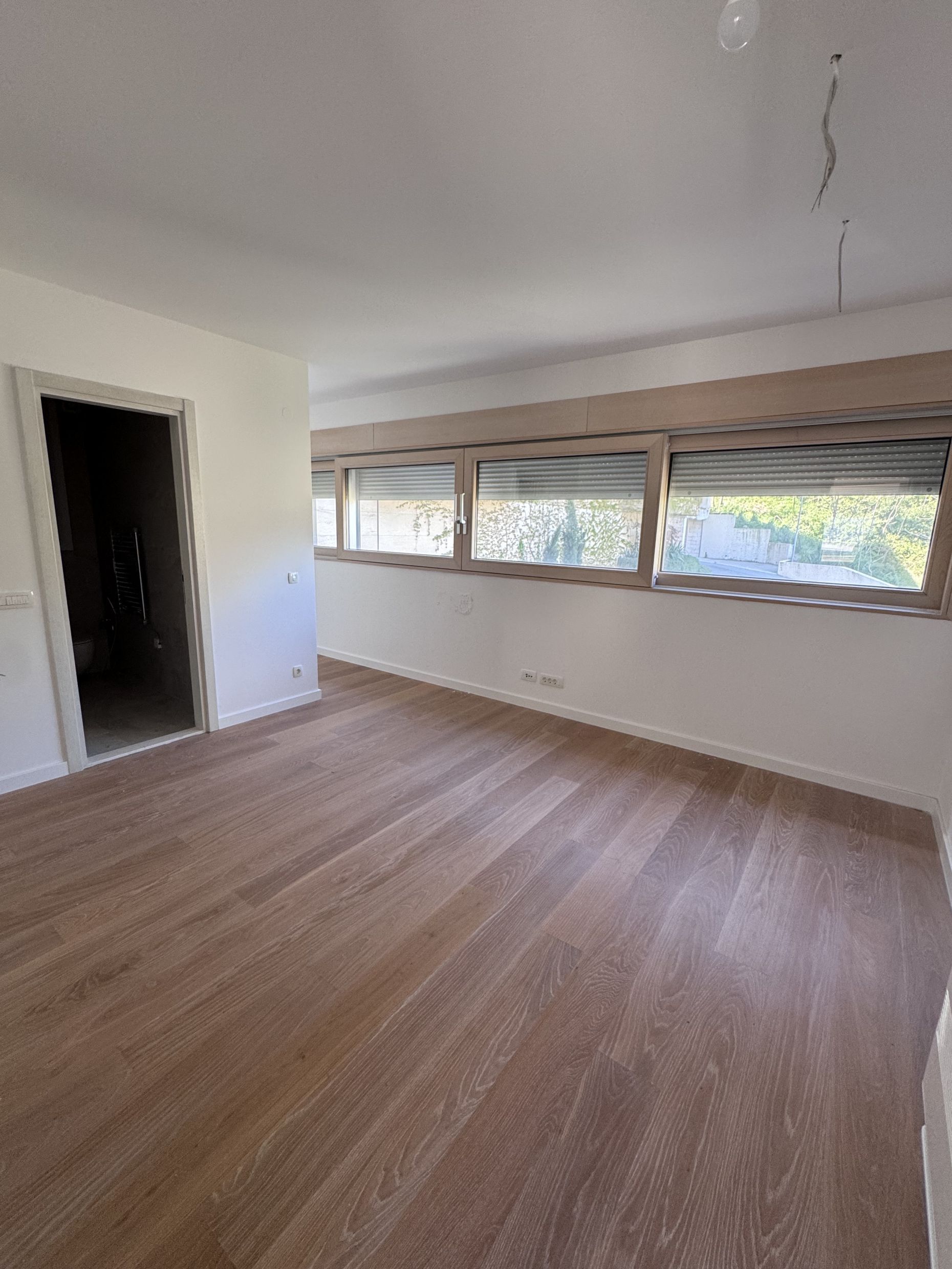Bright living room in a duplex in Kotor, Montenegro: finished interior, wooden floor, panoramic windows with shutters.