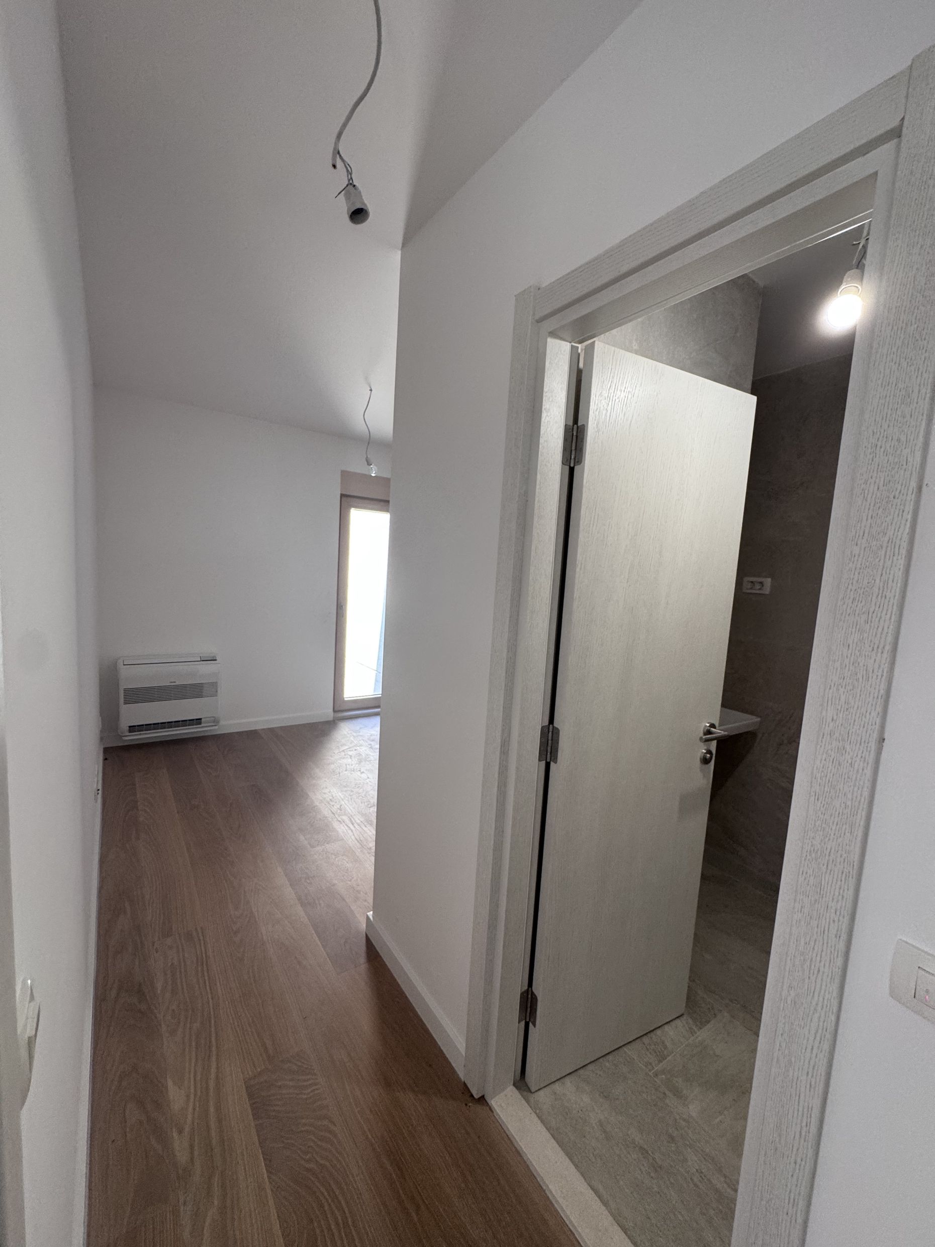 Apartment interior in Kotor, Montenegro: a bright room with parquet flooring, air conditioning, and an entrance to the bathroom.