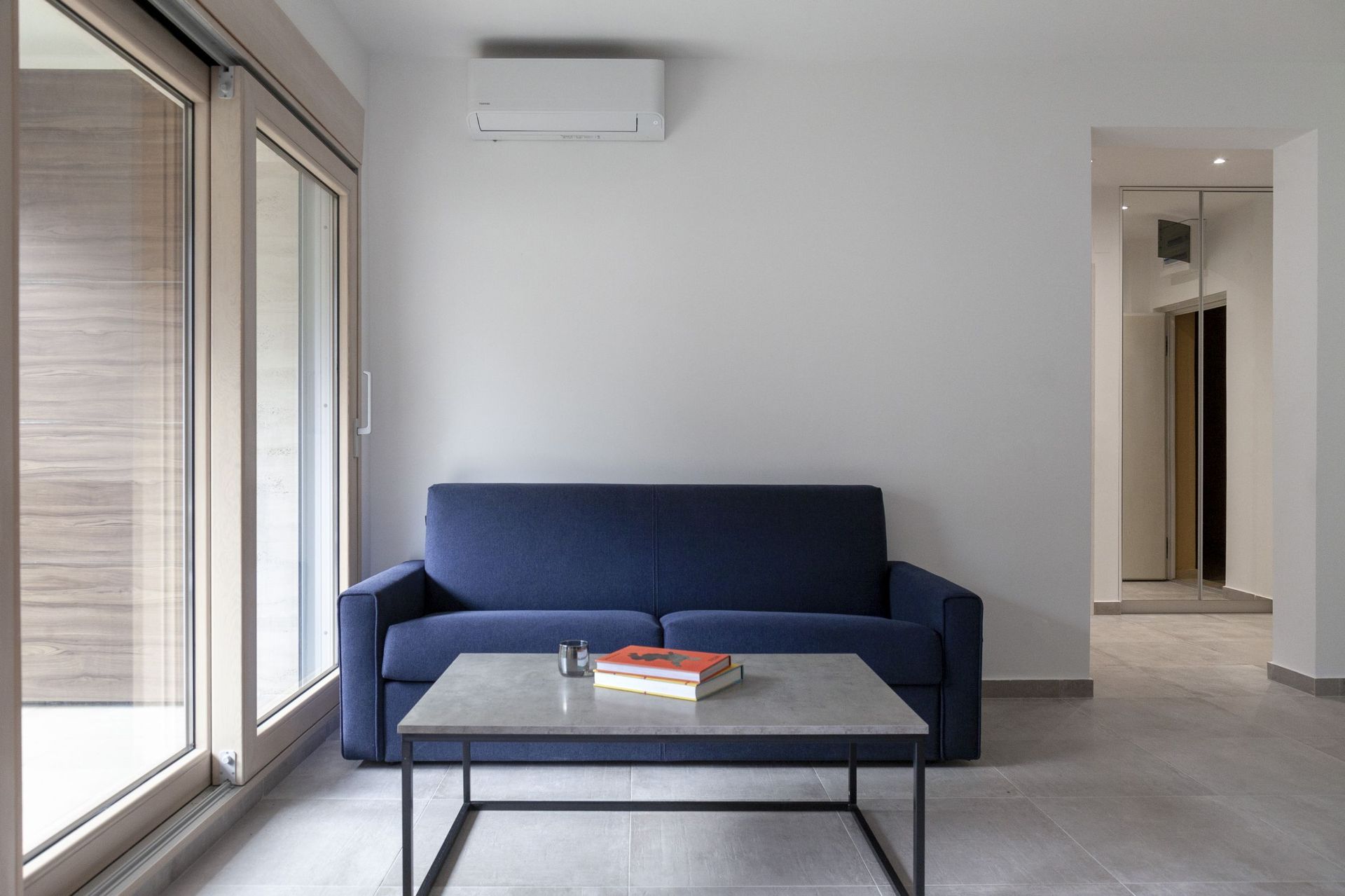 Modernes Wohnzimmer mit blauem Sofa und Couchtisch in einer Wohnung in Kotor, Montenegro. Panoramaverglasung.