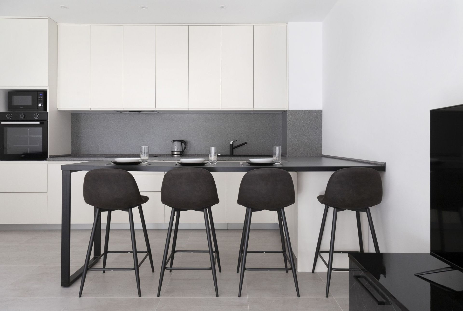 Moderne Küche mit Bartheke und Einbaugeräten in einer Wohnung, Kotor, Montenegro. Minimalistisches Interieur.
