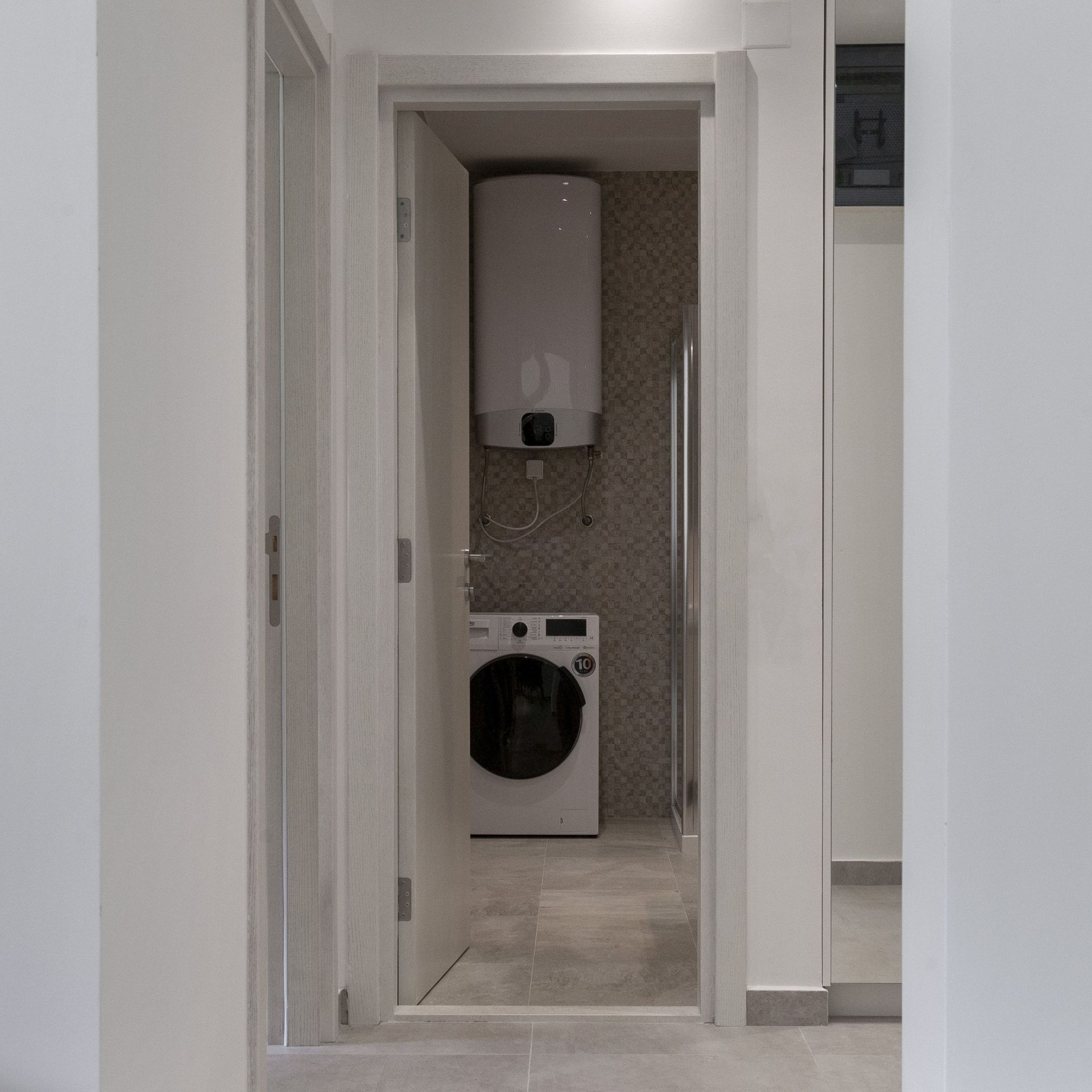 Badezimmer in einer Wohnung in Kotor, Montenegro: Waschmaschine, Boiler und Duschkabine in modernem Interieur.