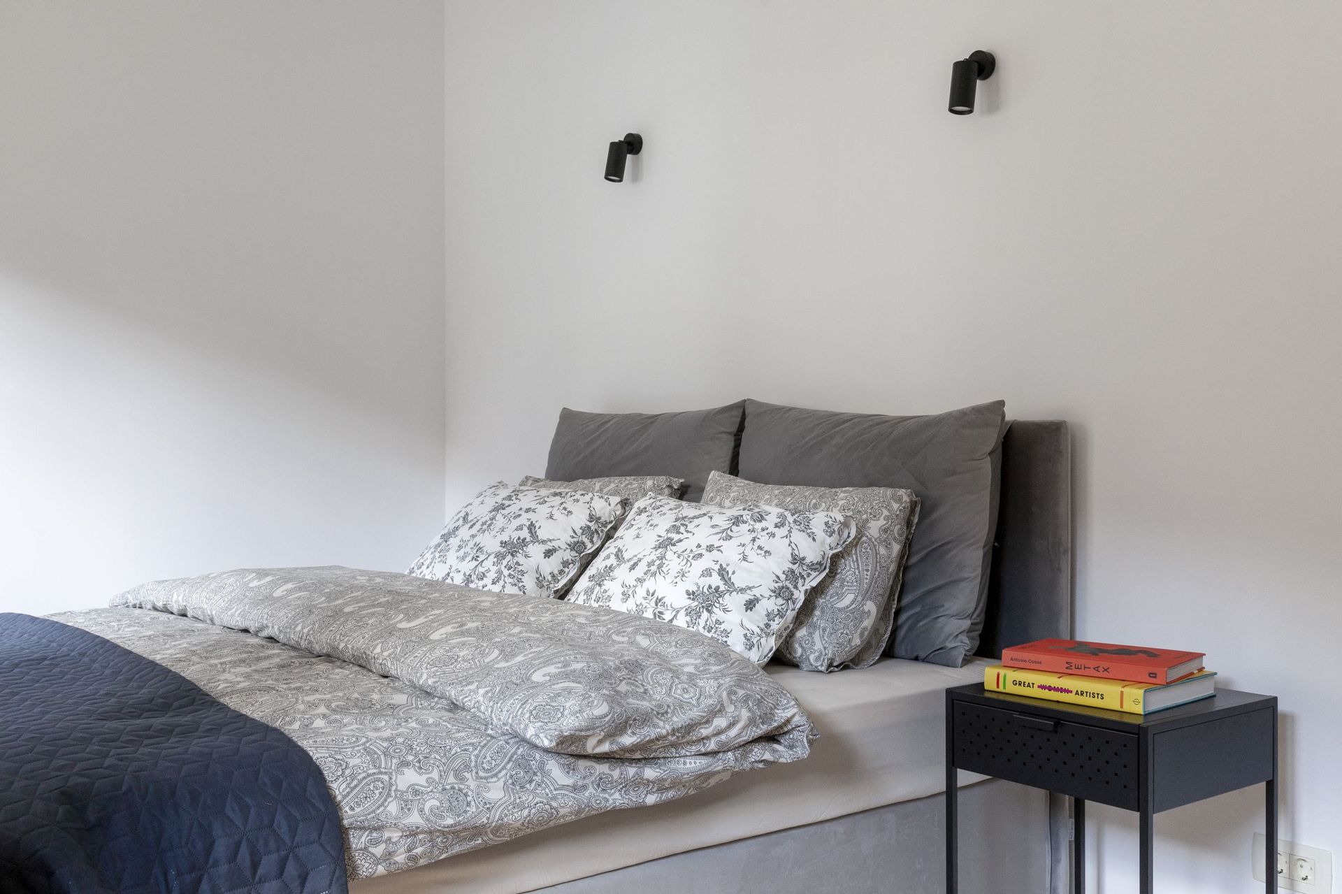 Gemütliches Schlafzimmer in einer Wohnung in Kotor, Montenegro: Doppelbett mit grauer Bettwäsche und schwarze Nachttische.