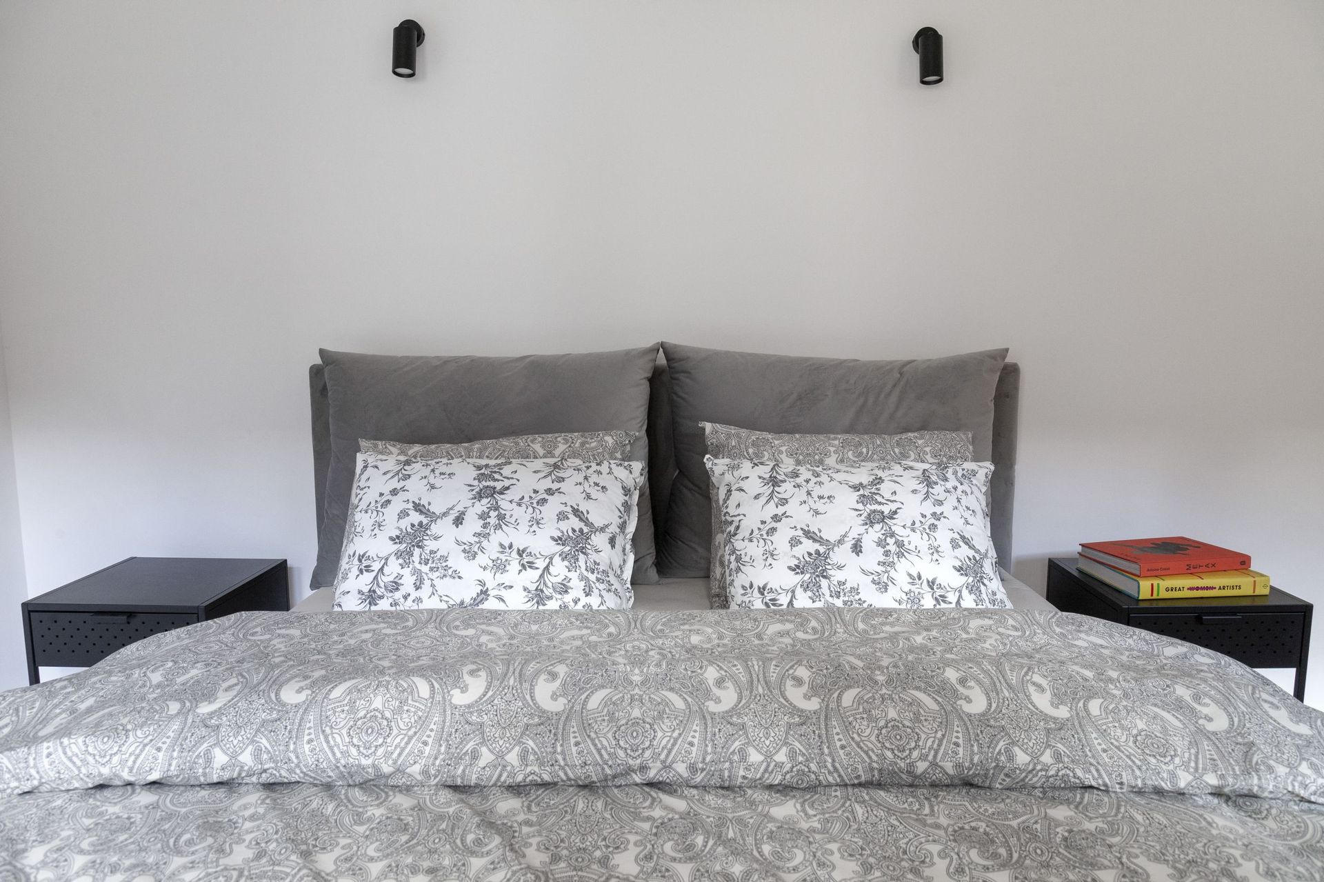 Modernes Schlafzimmer in einer Wohnung in Kotor, Montenegro: Doppelbett mit grauer Bettwäsche und schwarze Nachttische.
