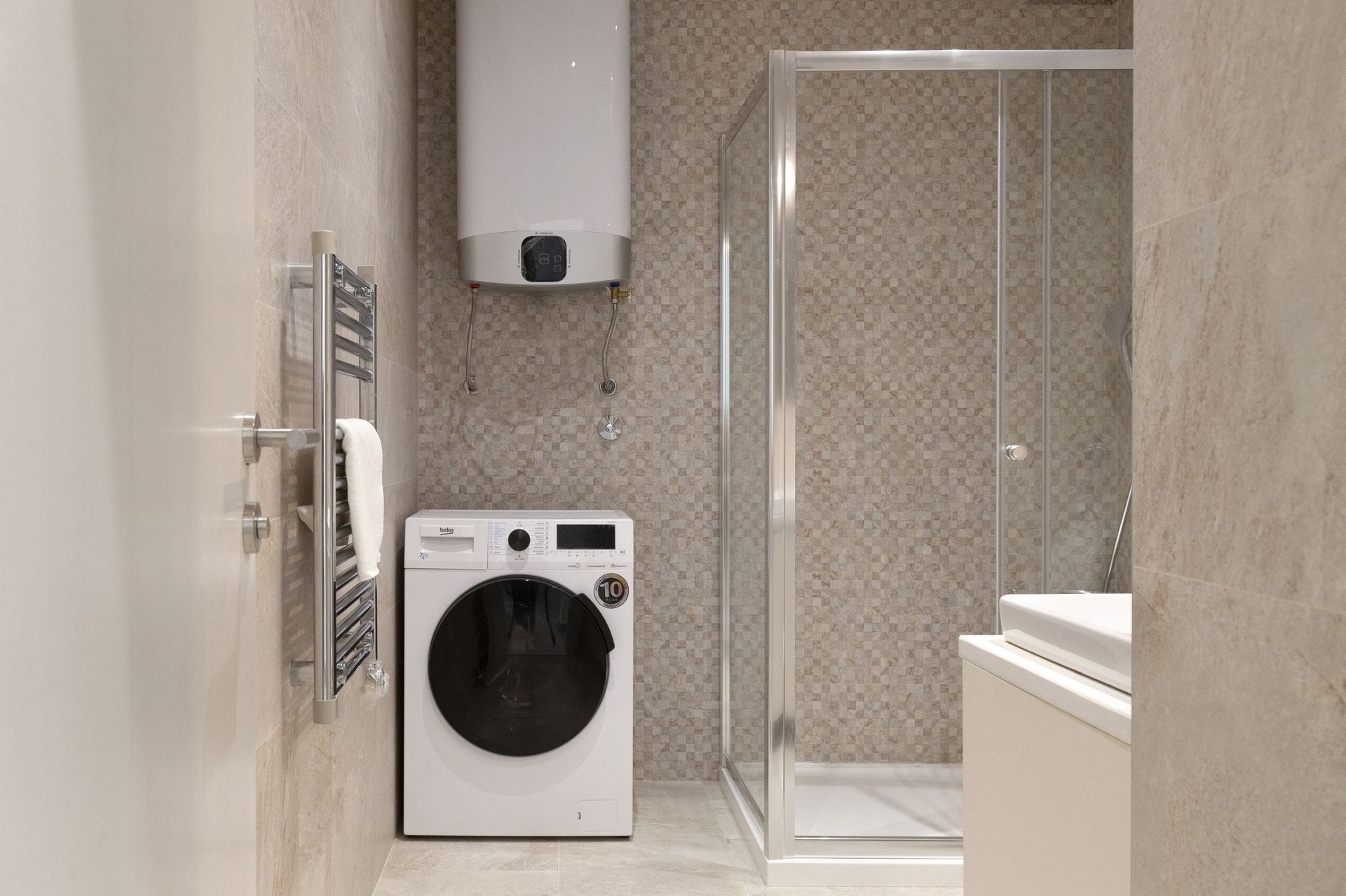 Modernes Badezimmer in einer Wohnung in Kotor, Montenegro: Duschkabine, Waschmaschine und Boiler.