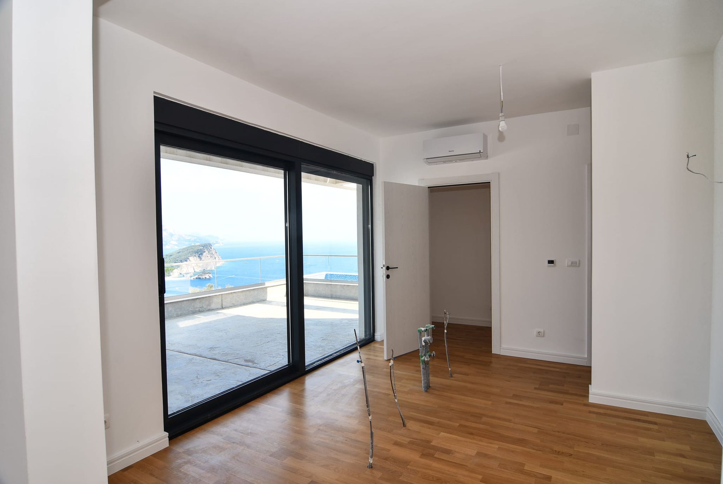 Wohnzimmer in einer Villa in Budva, Montenegro: Panoramafenster mit Meerblick, Terrasse und helle Innenausstattung.