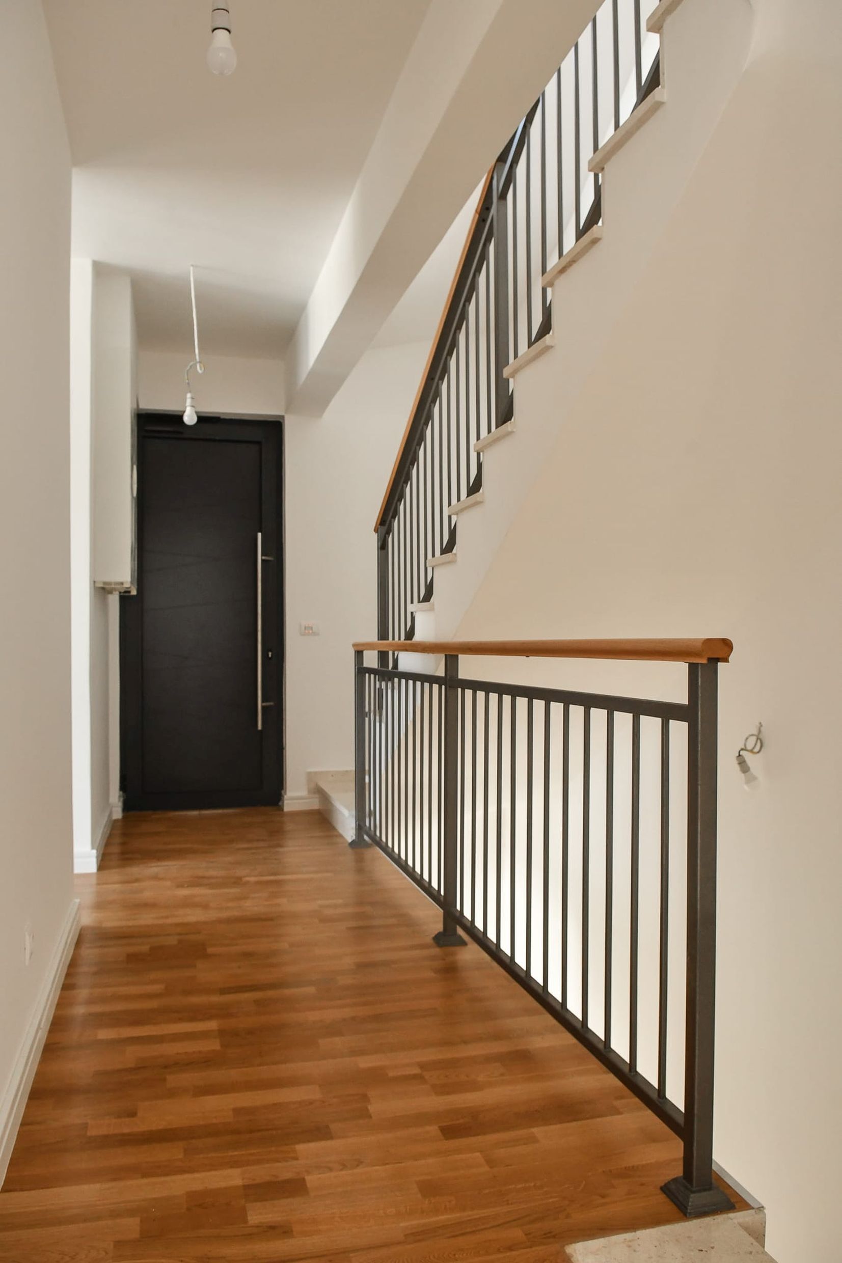 Innenraum einer Villa in Budva, Montenegro: moderne Treppe mit Metallgeländer und Holzboden im Flur.